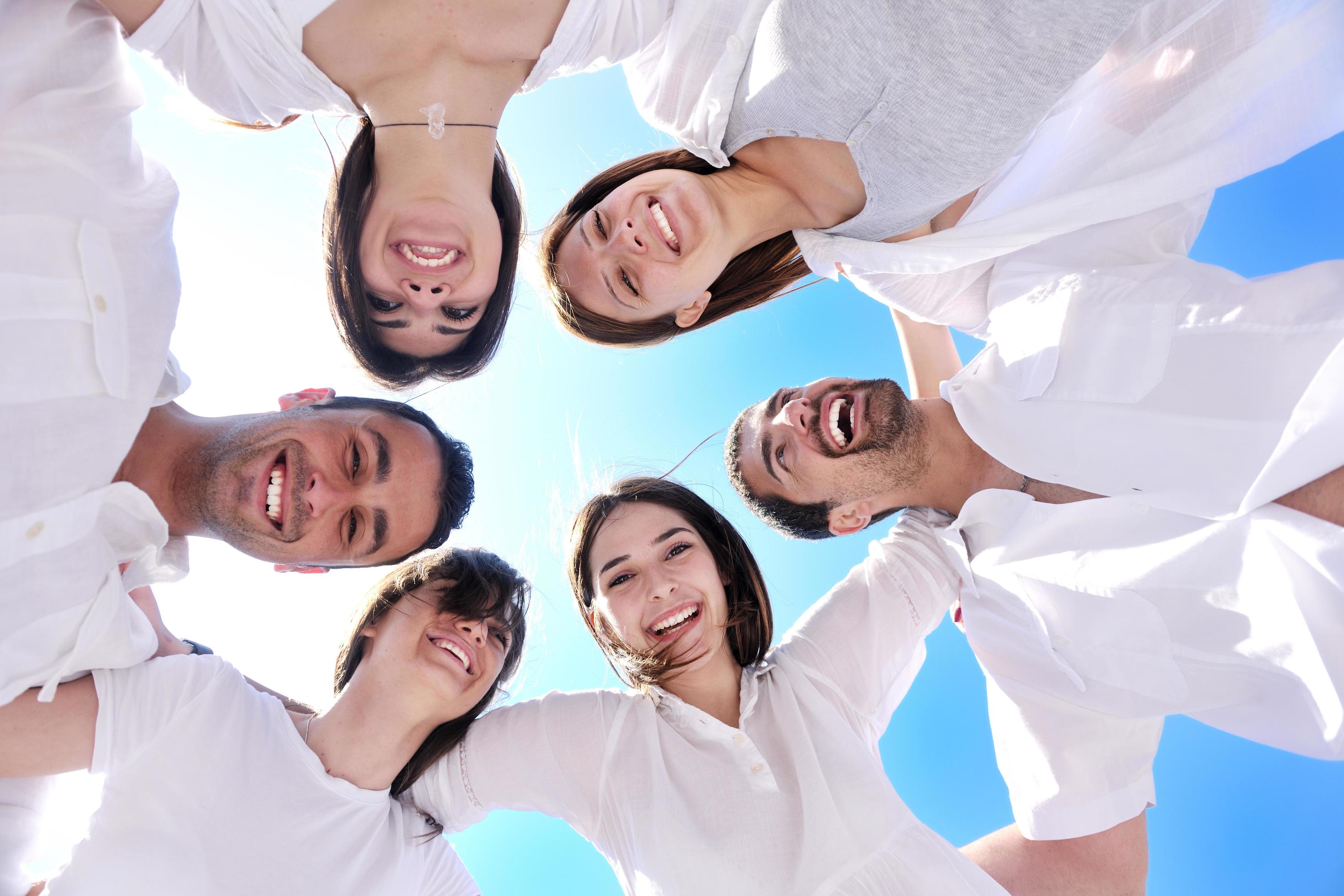 Group of happy young people in circle at beach Stock Free