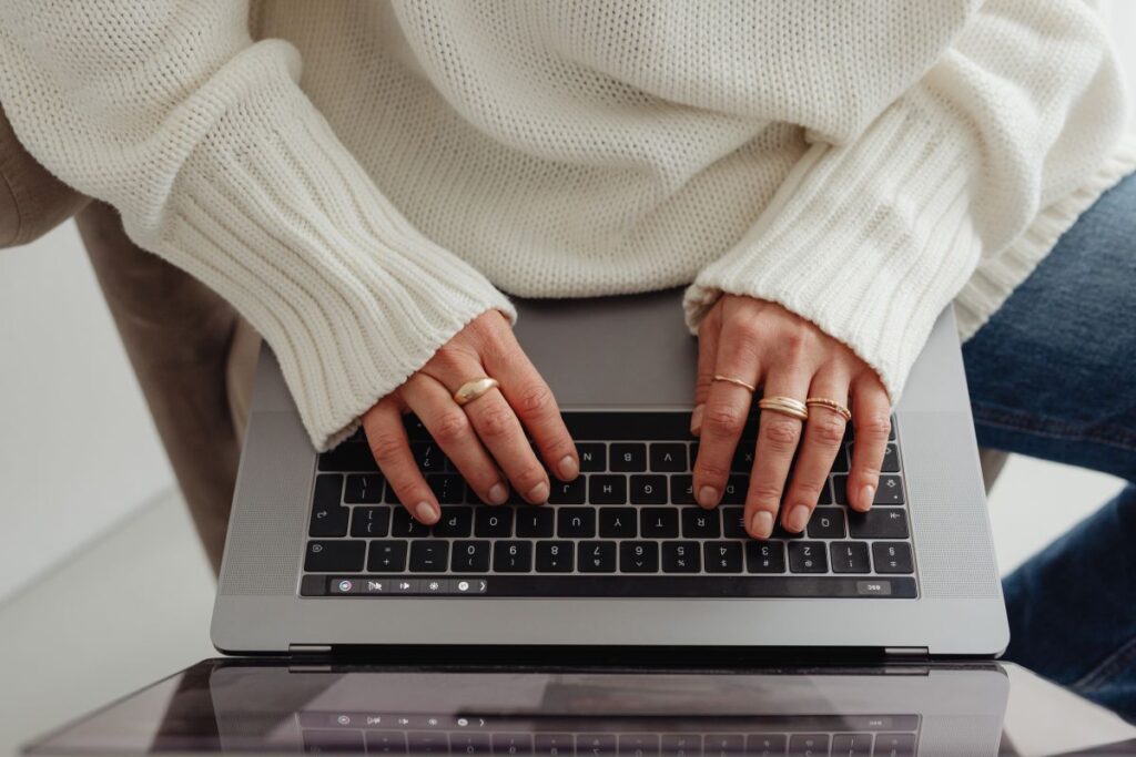 Woman in a white sweater – jewelry – laptop work – fashion Stock Free