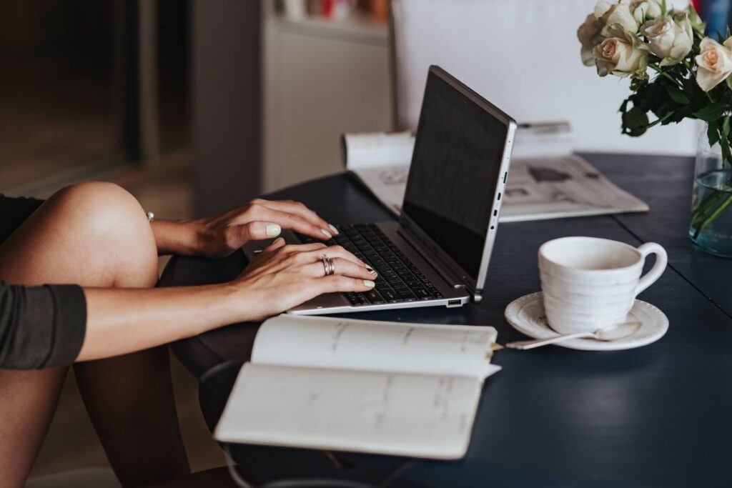 Woman using a laptop by a round breakfast table Stock Free