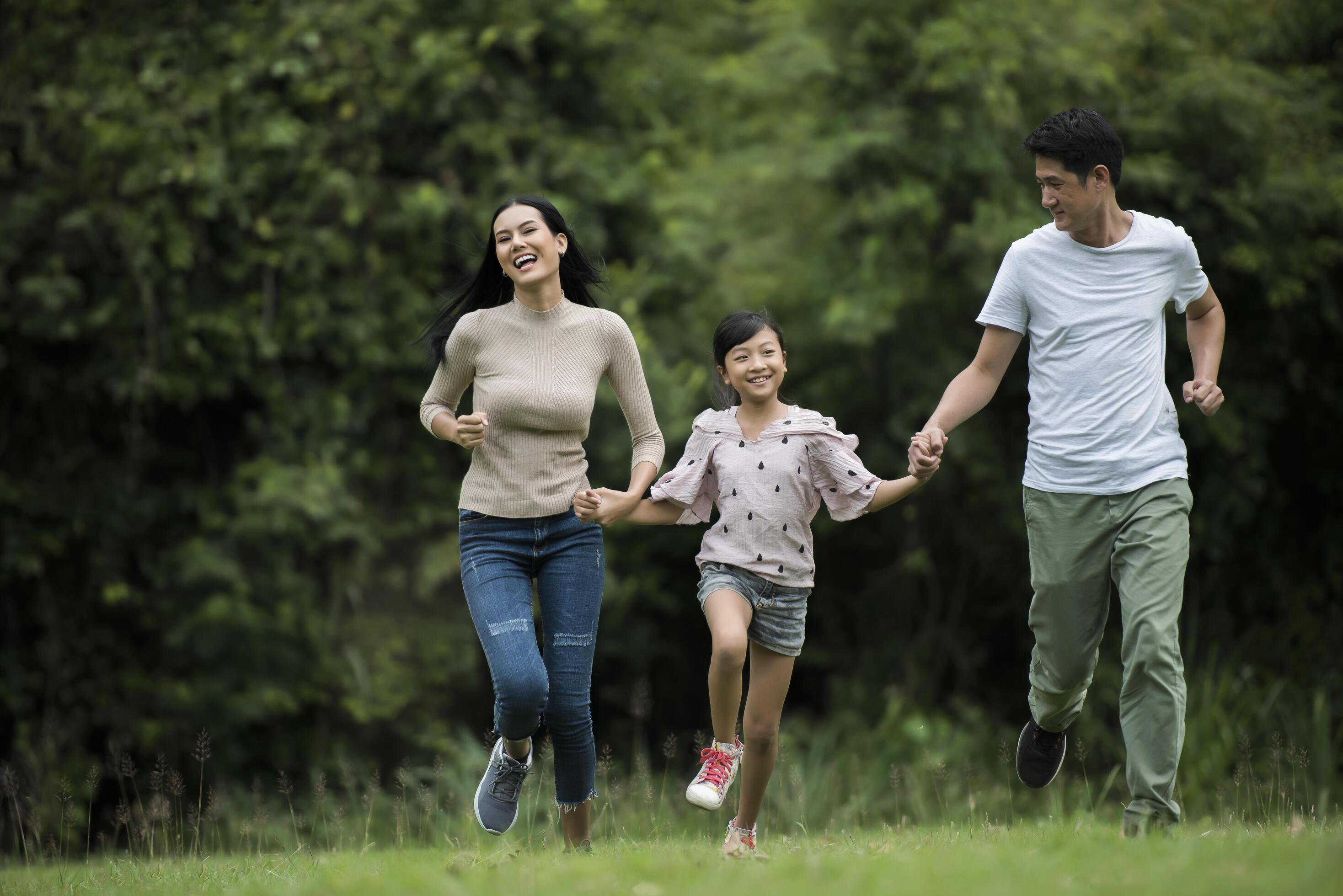 Happy family is having fun Mother, father and daughter are running in park. Stock Free