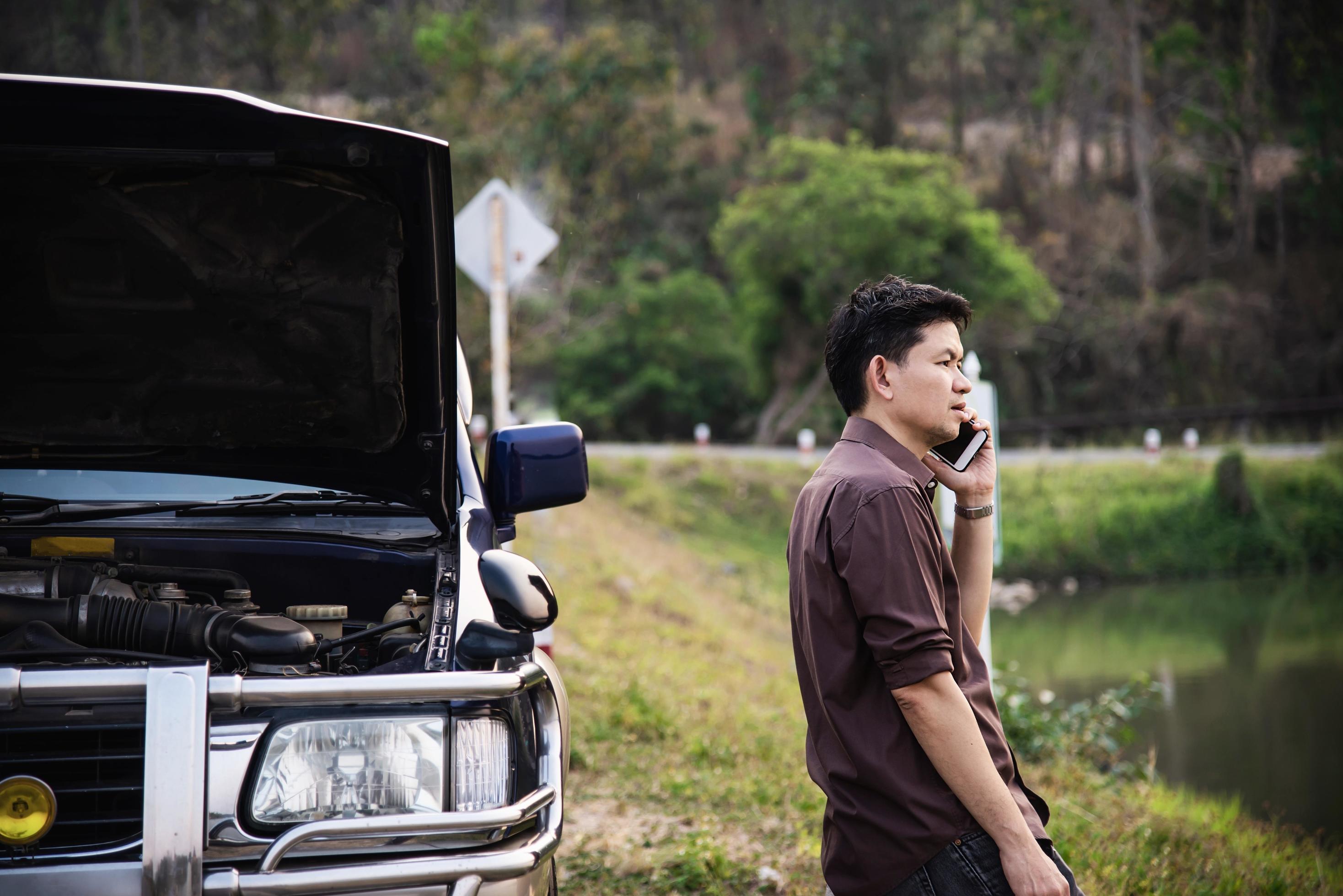 Man try to fix a car engine problem on a local road Chiang mai Thailand – people with car problem transportation concept Stock Free