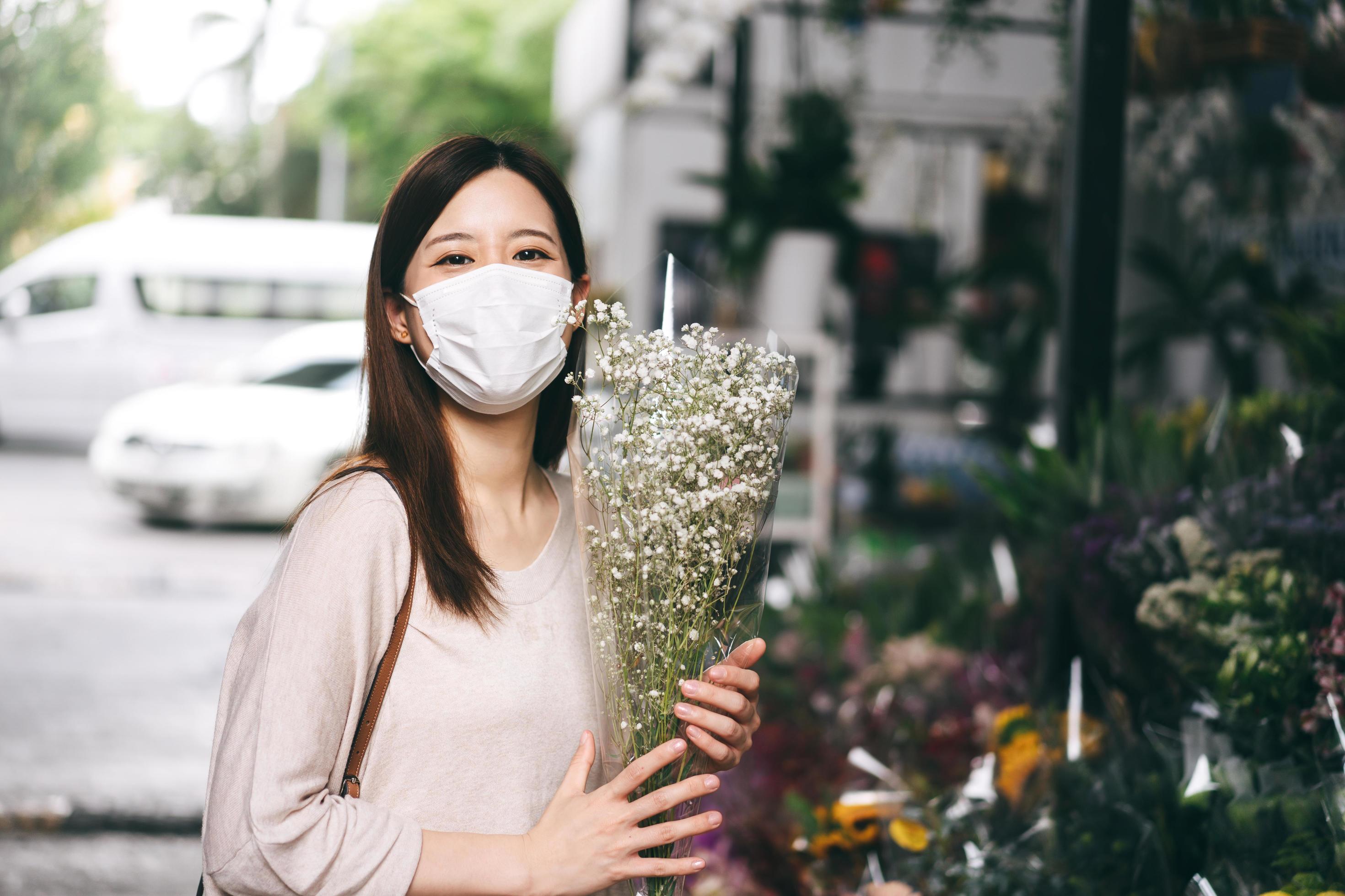 Adult asian woman wear face mask buying flower at kiosk on day. Stock Free