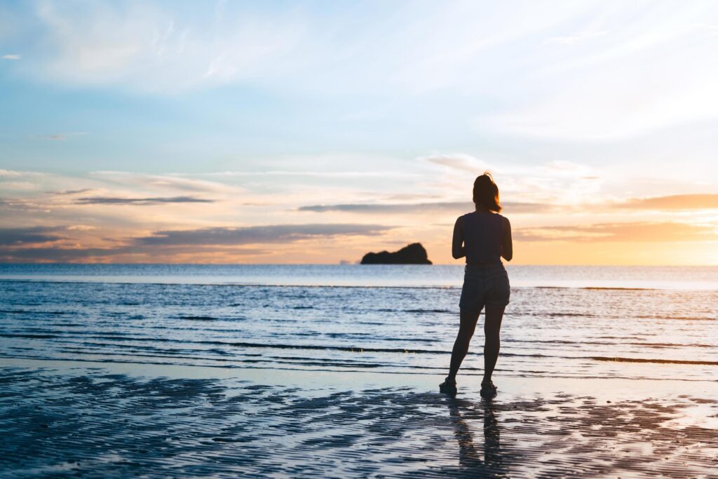 Rear view of young adult travel asian woman relax in nature on beach sea with morning sky Stock Free