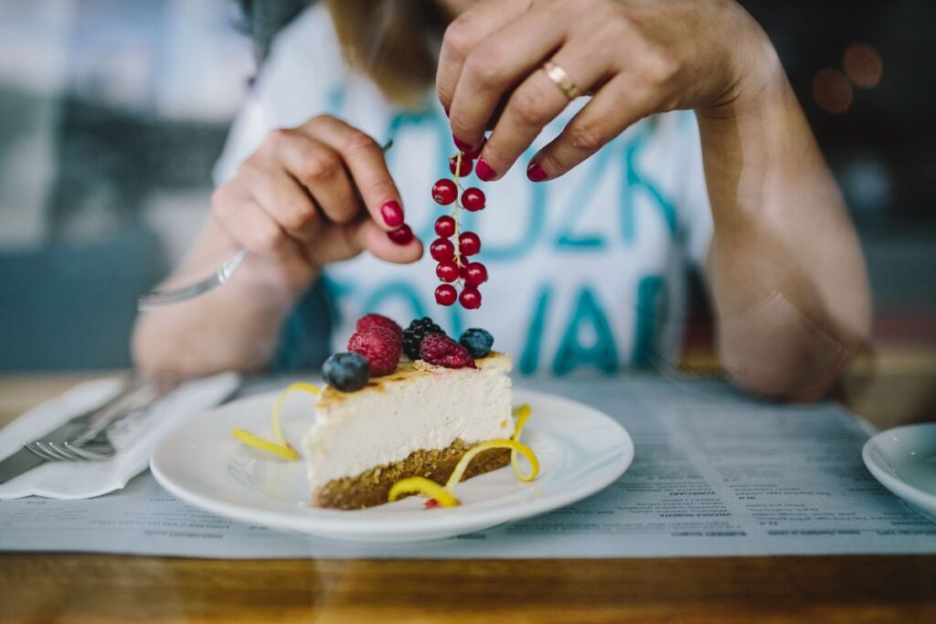 Woman Enjoying Cheese Cake and a Coffee with Fruits in a Cafeteria Stock Free