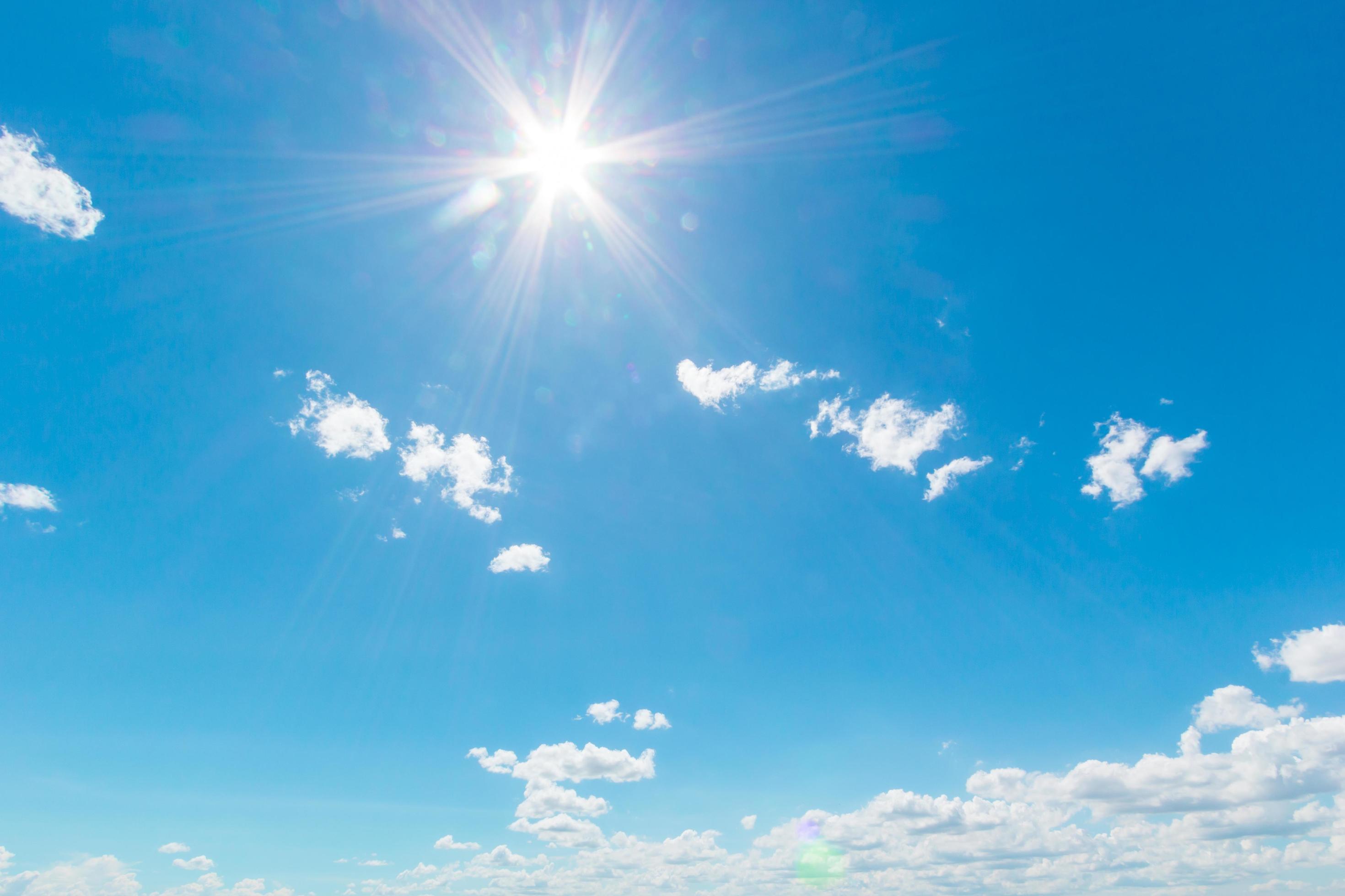 Natural abstract background of bright blue sky and fluffy white clouds on a sunny, light a flare and sun. Stock Free