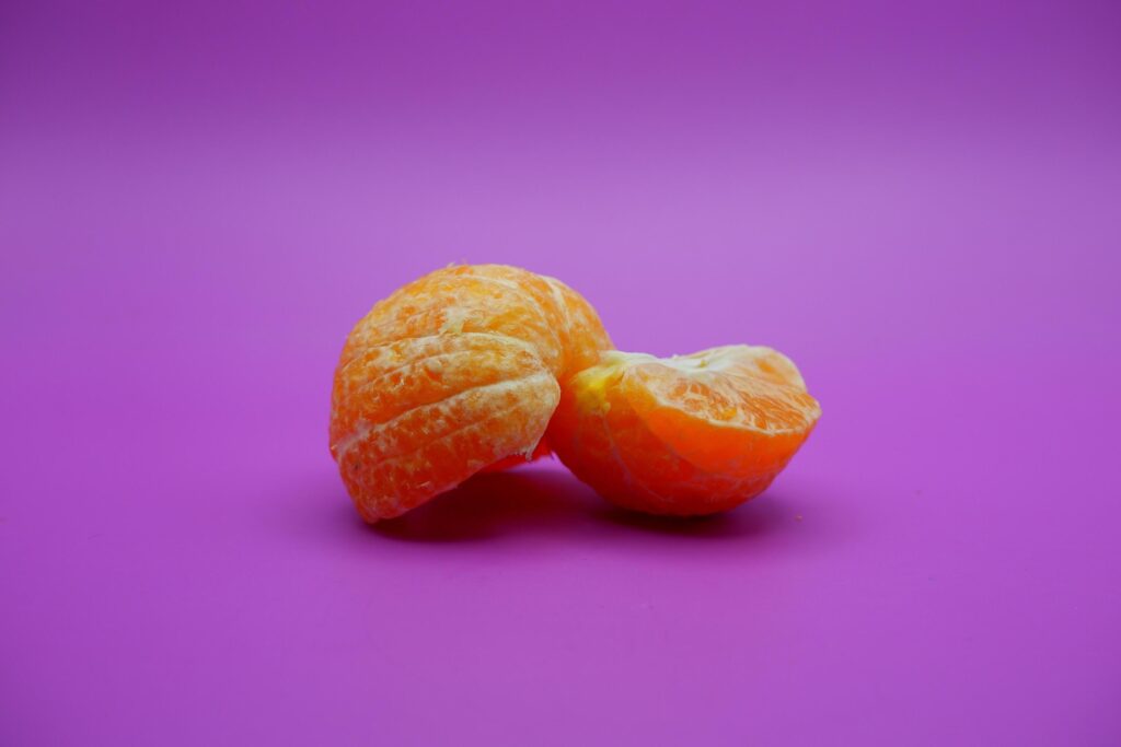 oranges that have been peeled and divided into several parts. orange isolated on purple background Stock Free