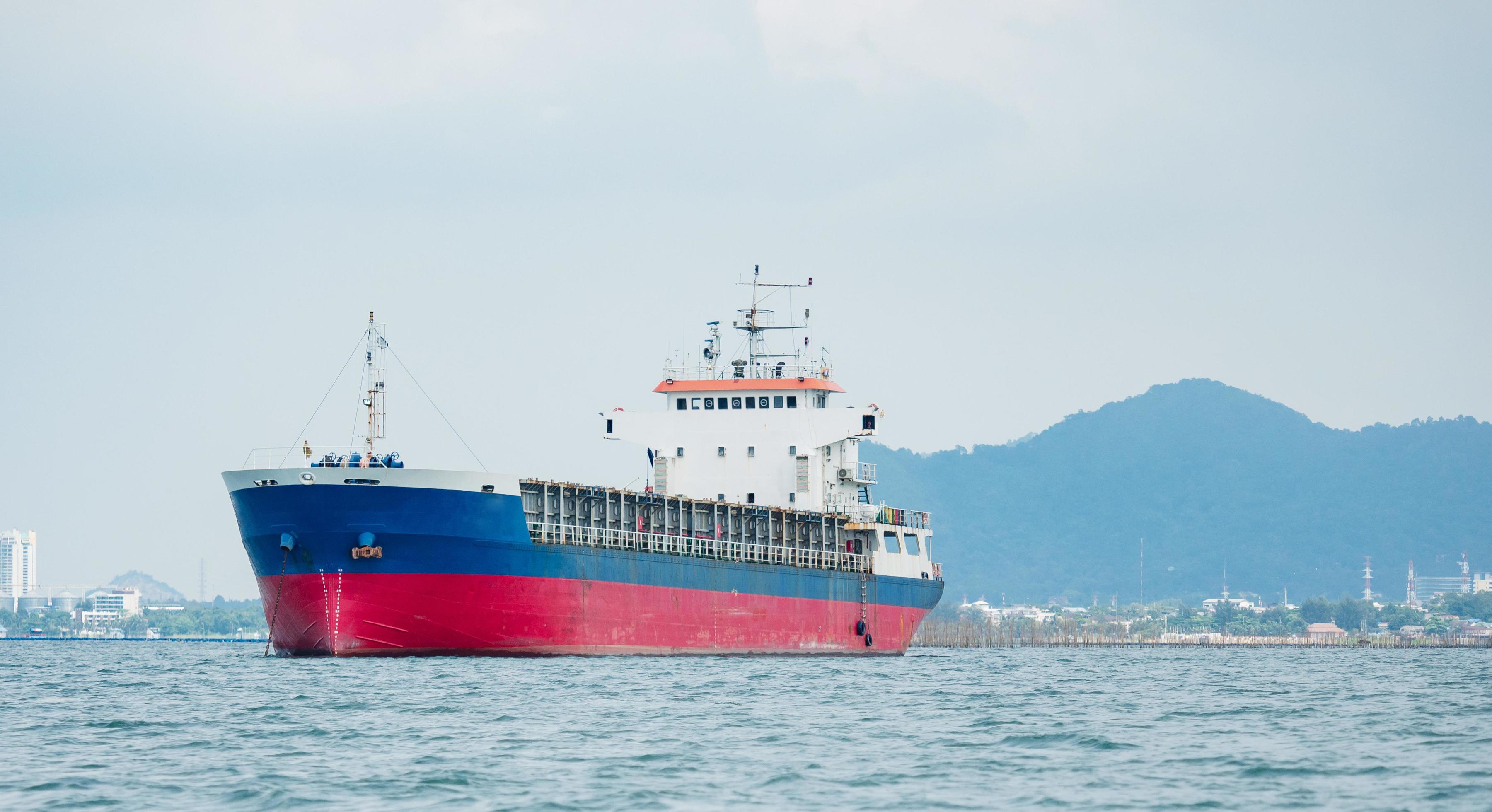 Cargo ship in the ocean with the island and mountain background,Transport ship on the sea front of dock and isle with the blue sky Stock Free