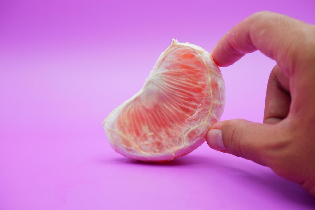 a slice of grapefruit isolated on a purple background. peeled grapefruit Stock Free