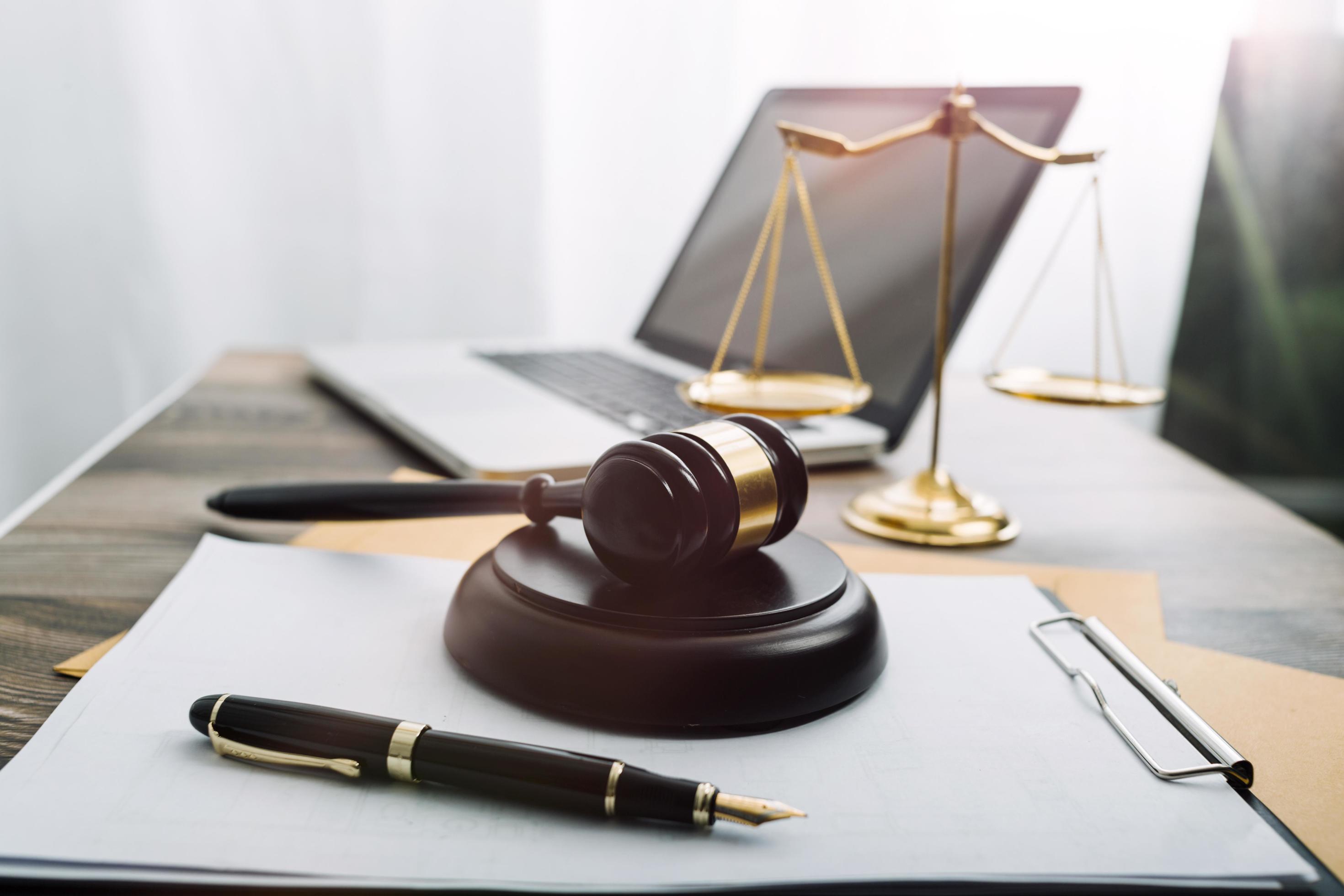 Justice and law concept.Male judge in a courtroom with the gavel, working with, computer and docking keyboard, eyeglasses, on table in morning light Stock Free