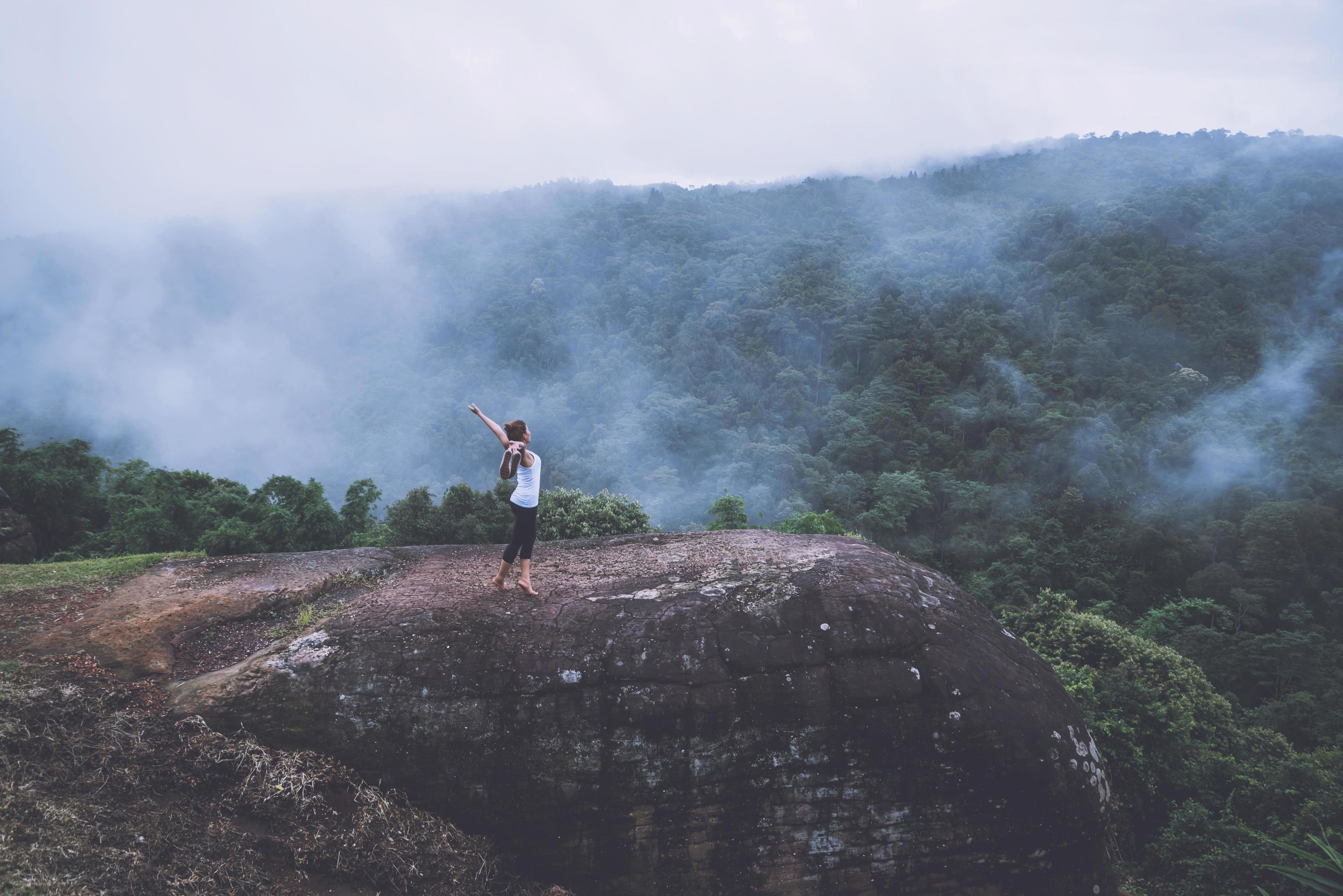 Young woman exercises yoga in the mountains. Asian woman travel nature. Travel relax exercises yoga touch natural fog on mountain peak. Stock Free