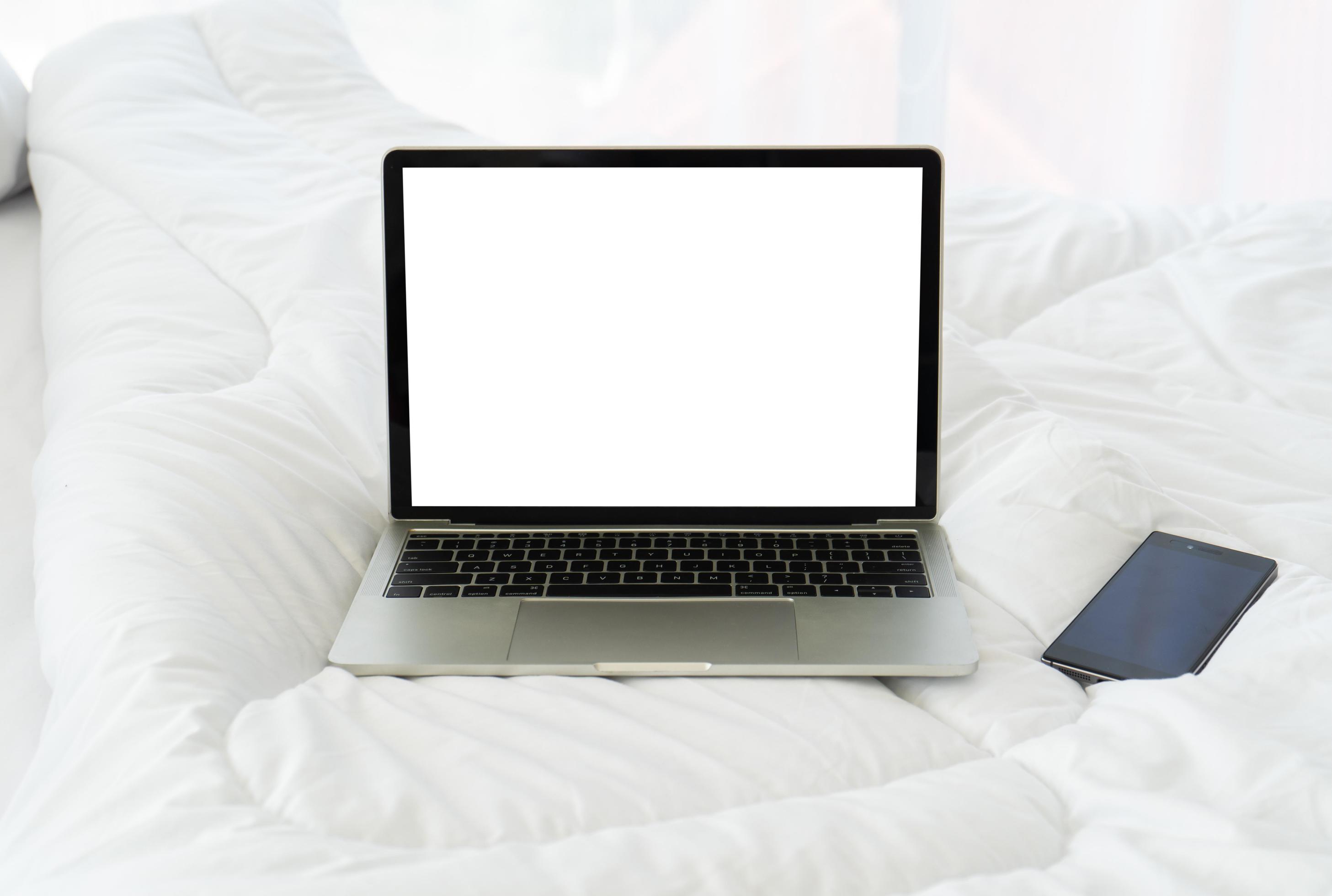 Blank screen notebook computer and smartphone on bed,Holiday concept Stock Free