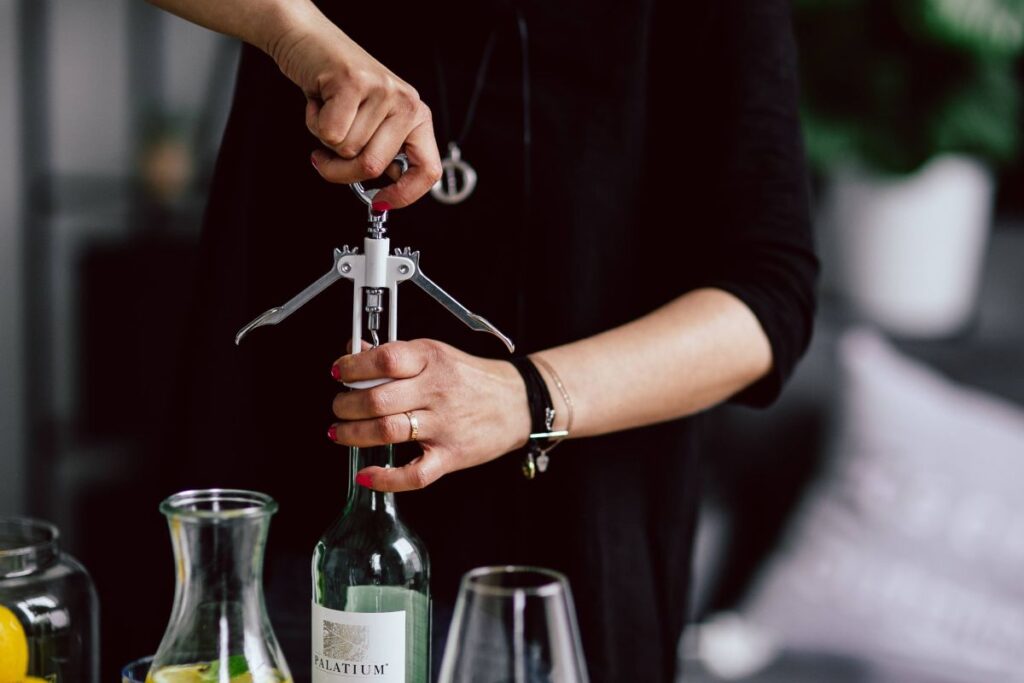 Hands opening wine bottle with corkscrew Stock Free