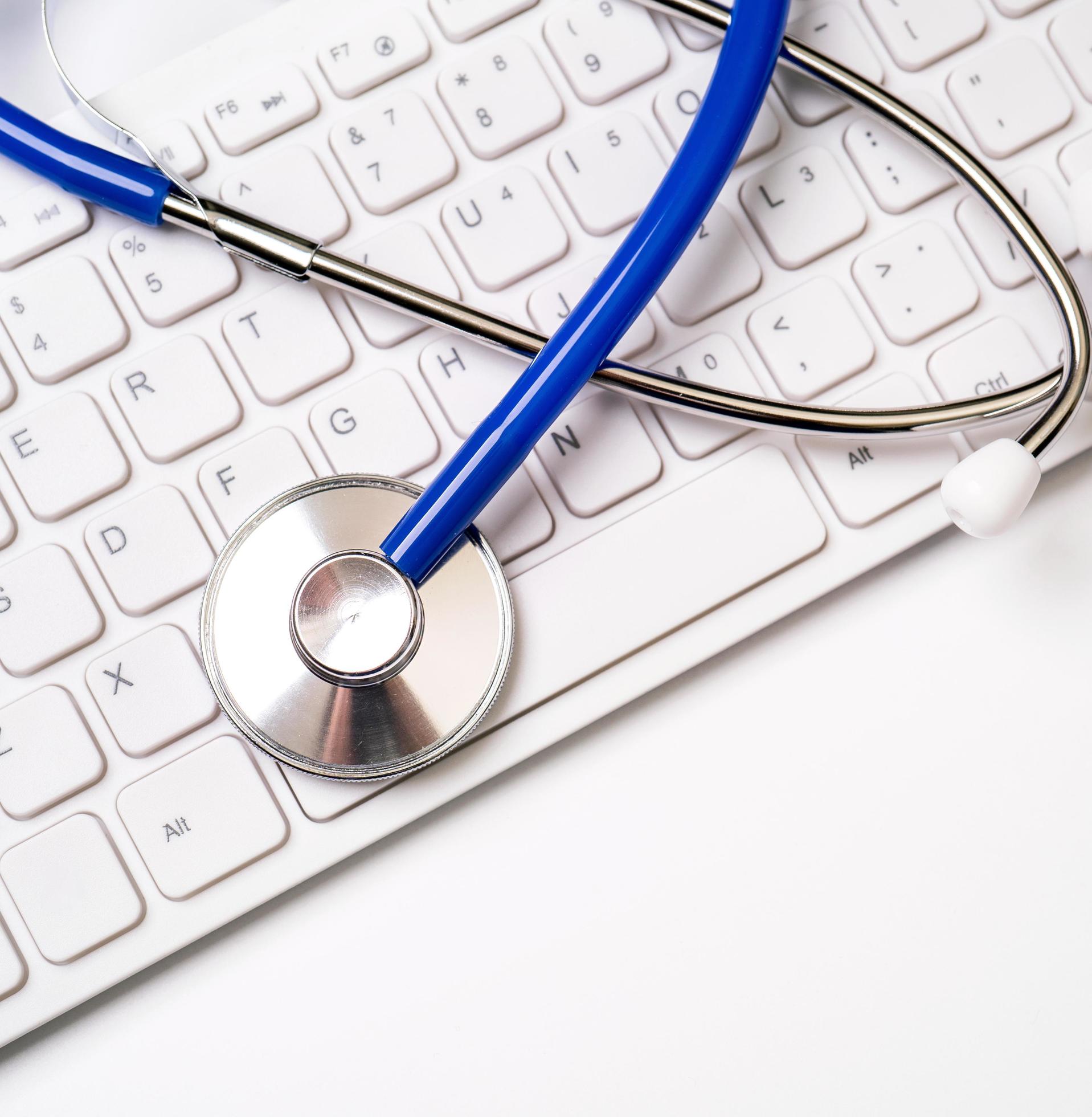 Blue stethoscope on computer keyboard on white table background. Online medical information treatment technology concept, close up, macro, copy space Stock Free