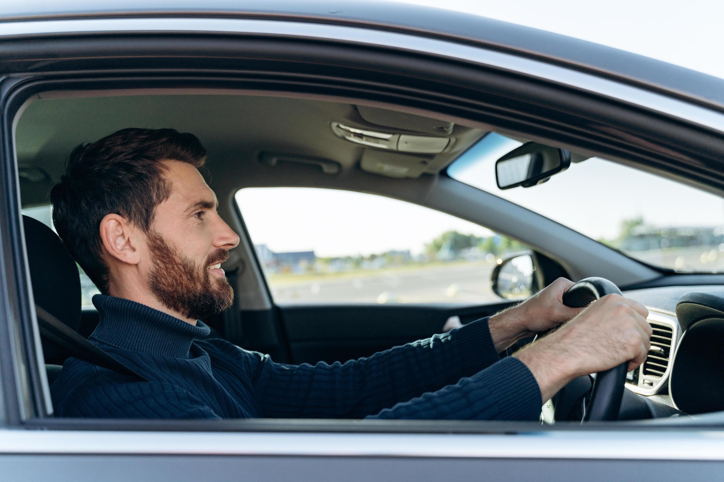 Side view of the handsome businessman driving car before buying. Attractive elegant man in business closes driving car. Transportation concept Stock Free