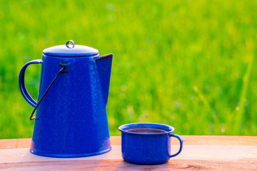 Kettle, blue enamel, and coffee mugs On an old wooden floor, Blurred background of rice fields at sunrise. Stock Free