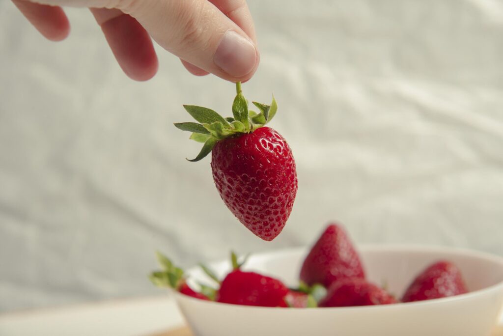 Close-up of strawberries in a woman hands against the background of strawberries in a bowl Stock Free