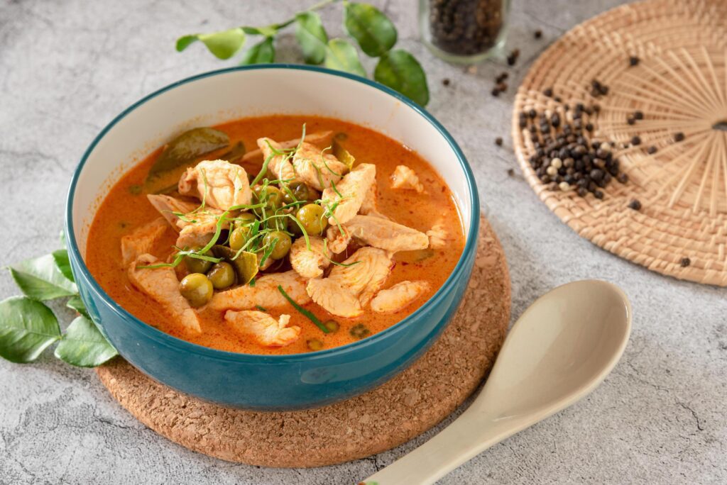 Thai red curry with minced chicken, fresh vegetable and herb in bowl on table, Thai menu and background Stock Free