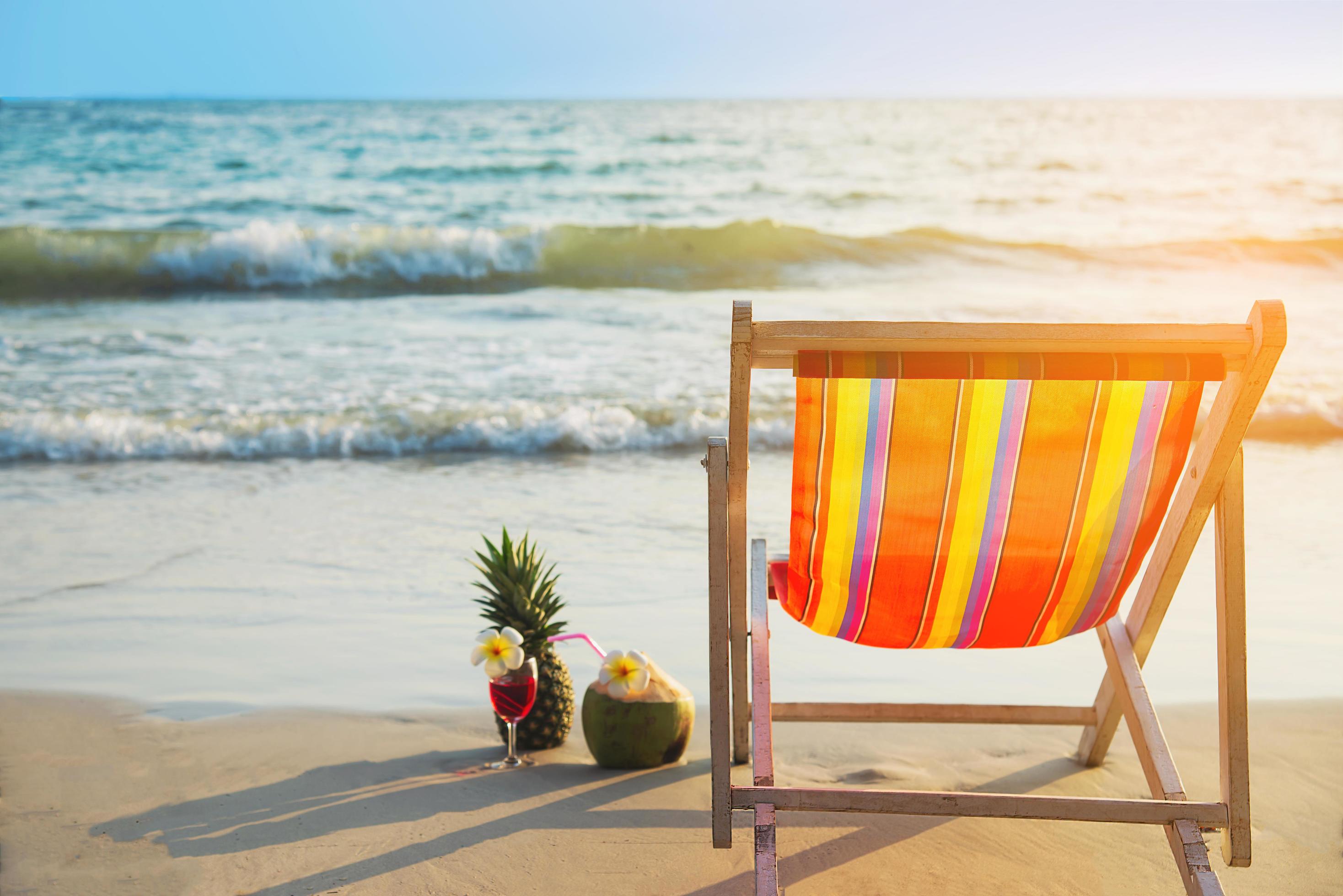 Relax beach chair with coconut pineapple and cocktail glass on clean sand beach with blue sea and clear sky – sea nature background relax concept Stock Free