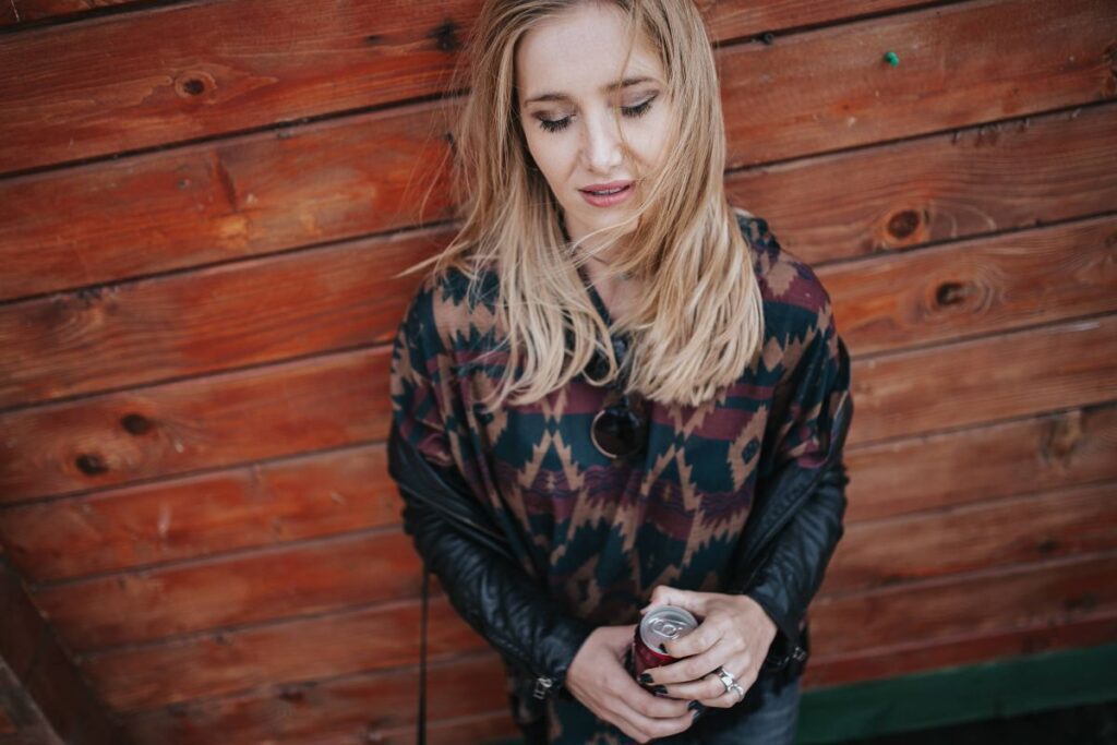 Blonde woman with a can of coke by a wooden wall Stock Free