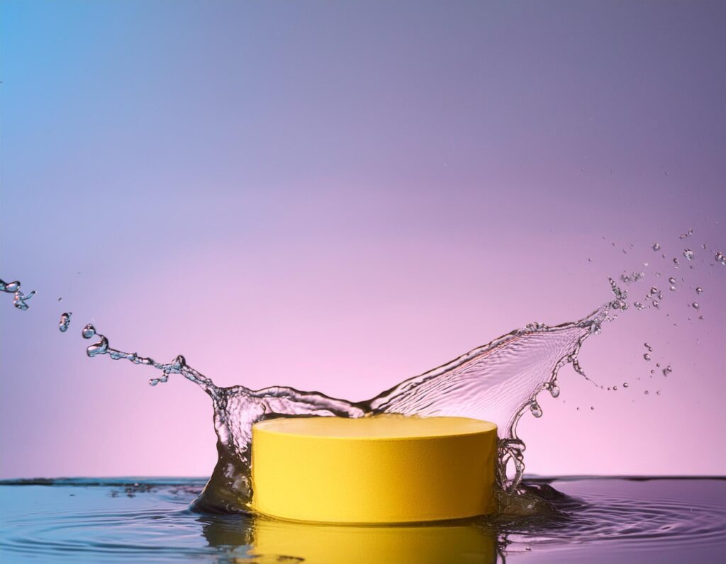 empty yellow podium mockup with water splash on a gradient background for product display Stock Free