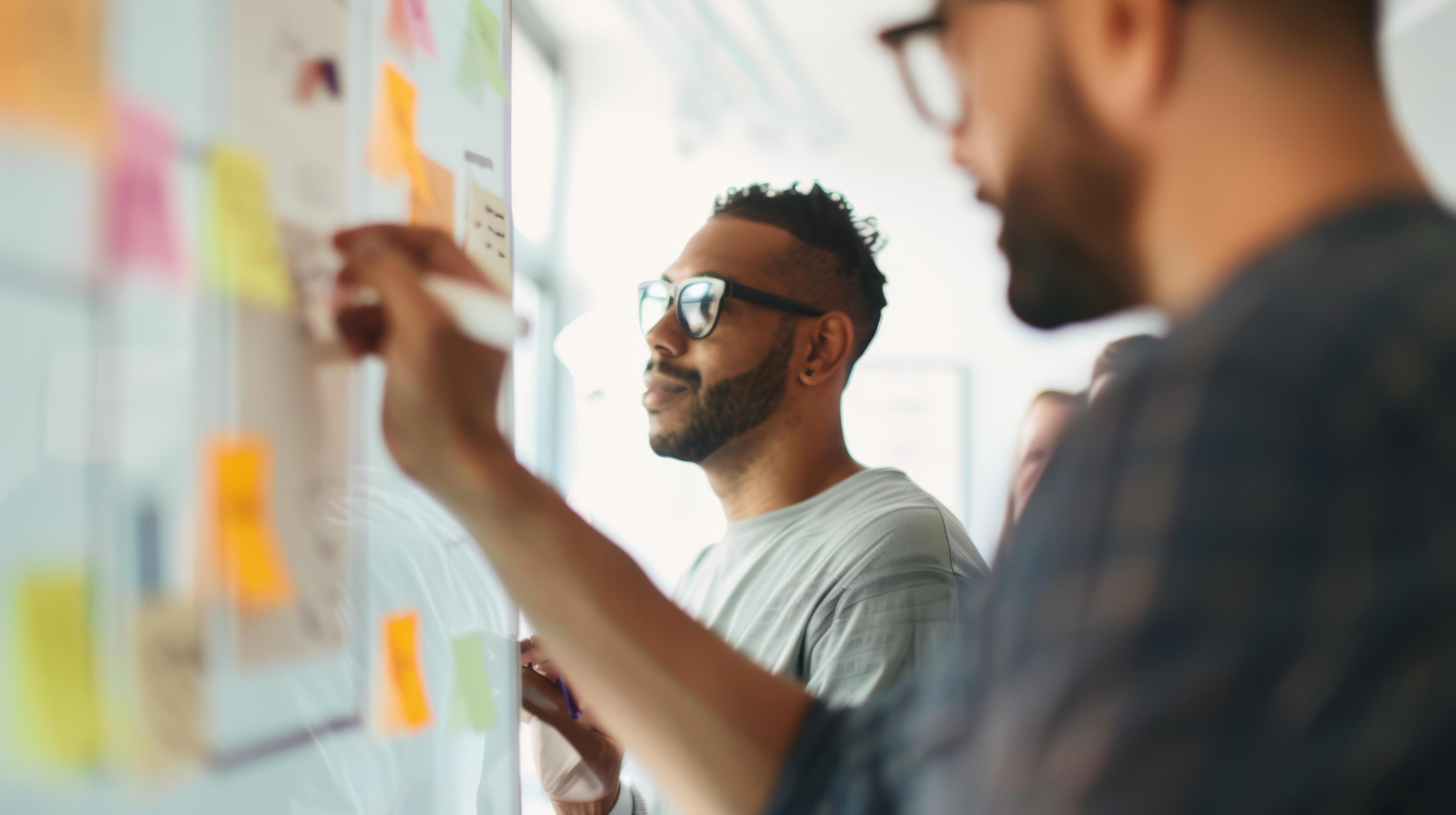 Team collaborating on a project with sticky notes on a board. Focused professionals brainstorming business ideas Stock Free