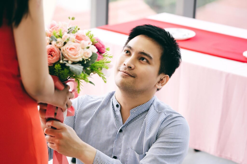 Asian couple with flower bouquet at dinner table on anniversary. Stock Free