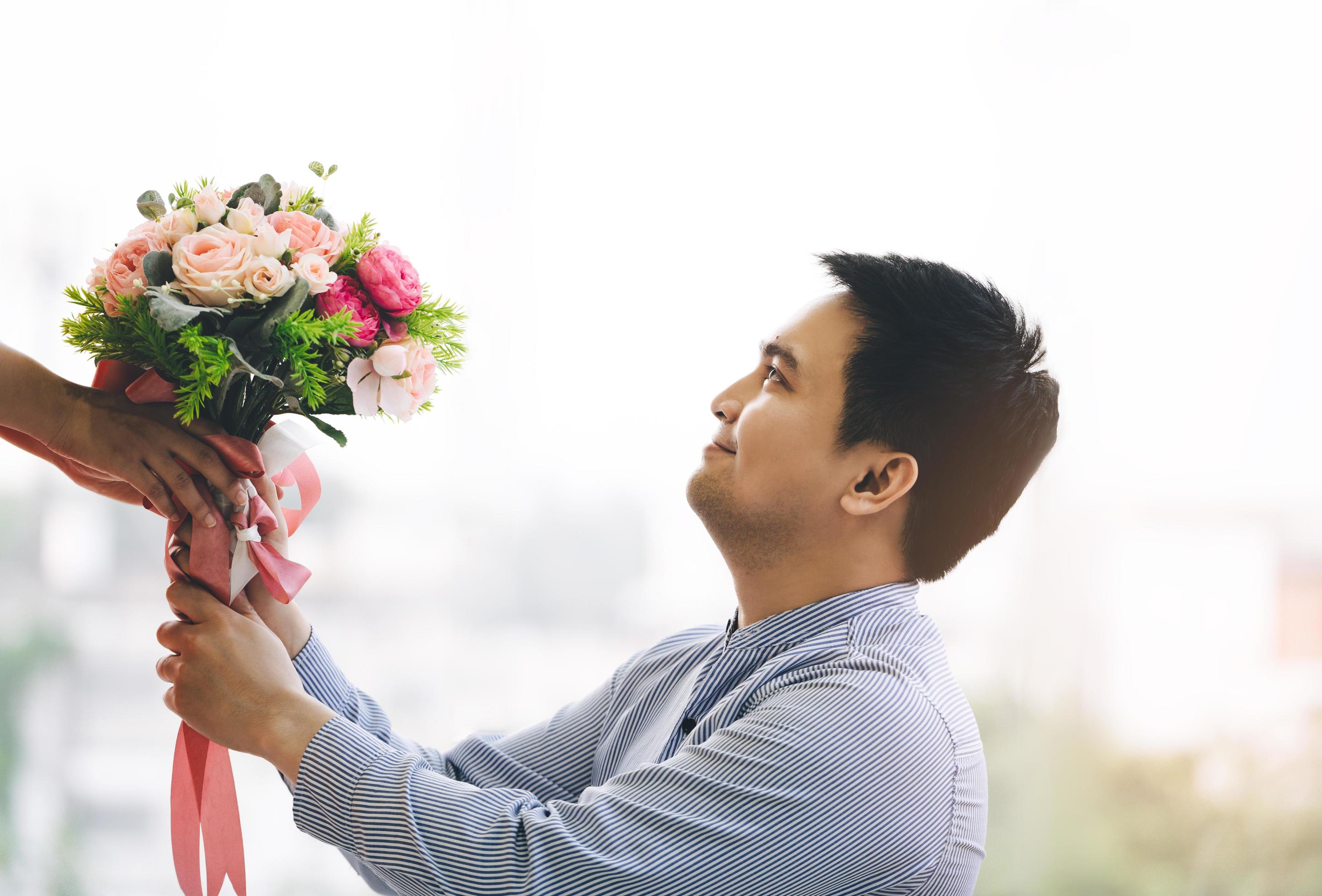 Adult asian man give a flower bouquet to girlfriend in romantic date. Stock Free