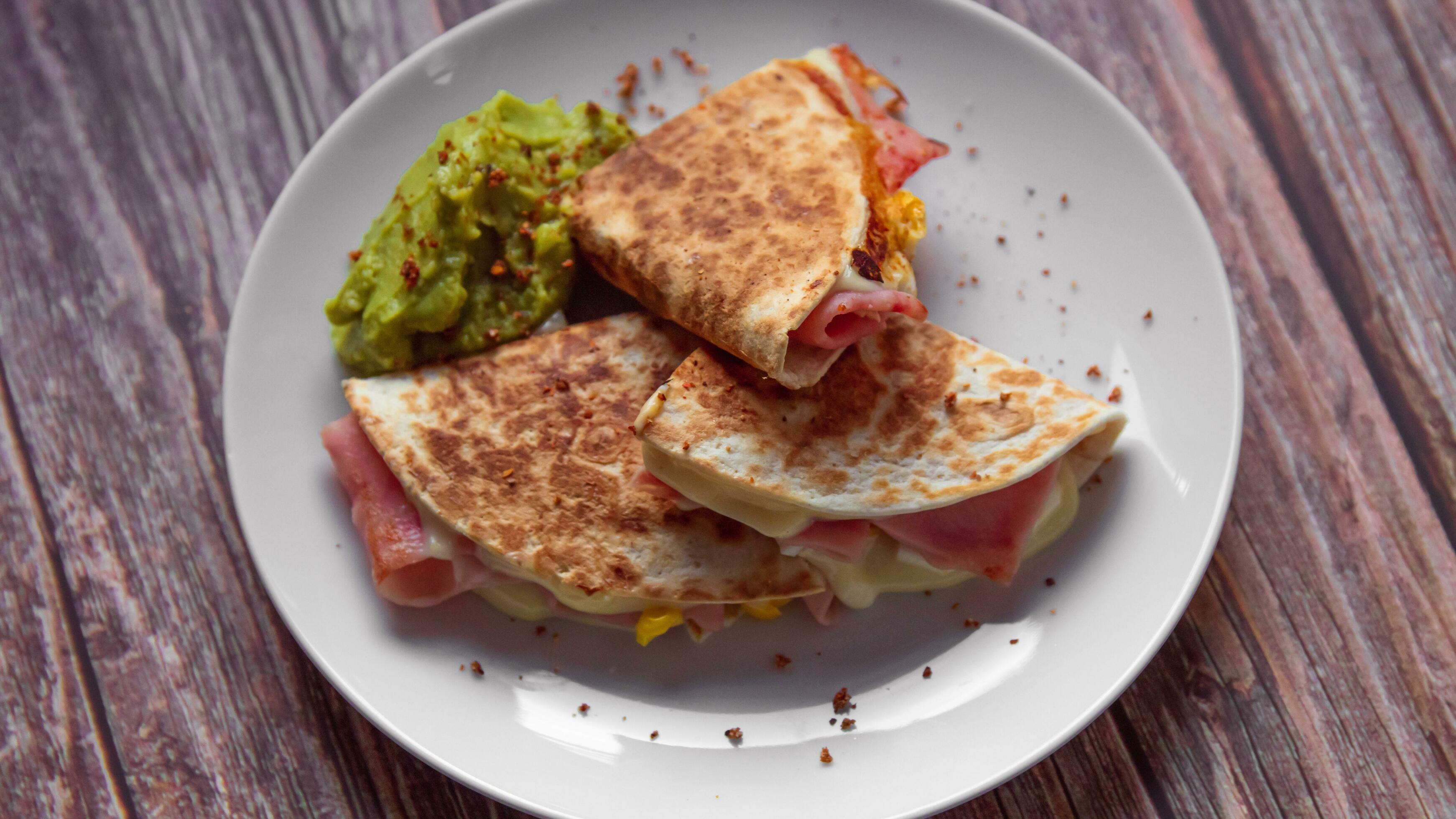 A plate of food with a quesadilla and guacamole on it. Stock Free