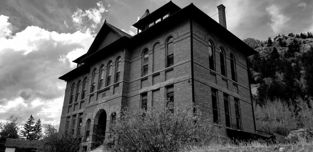 A black and white photo of an old building in a small town. Stock Free