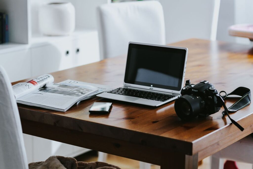 Silver laptop with various items on a table Stock Free