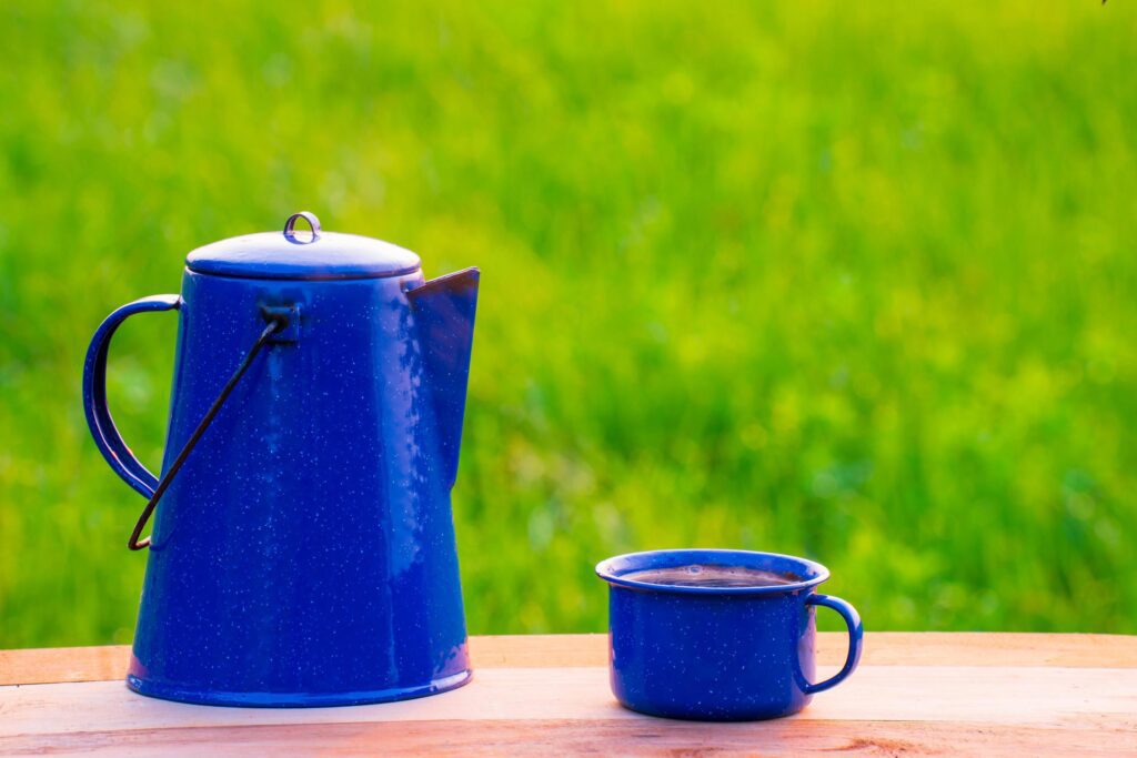 Kettle, blue enamel, and coffee mugs On an old wooden floor, Blurred background of rice fields at sunrise. Stock Free