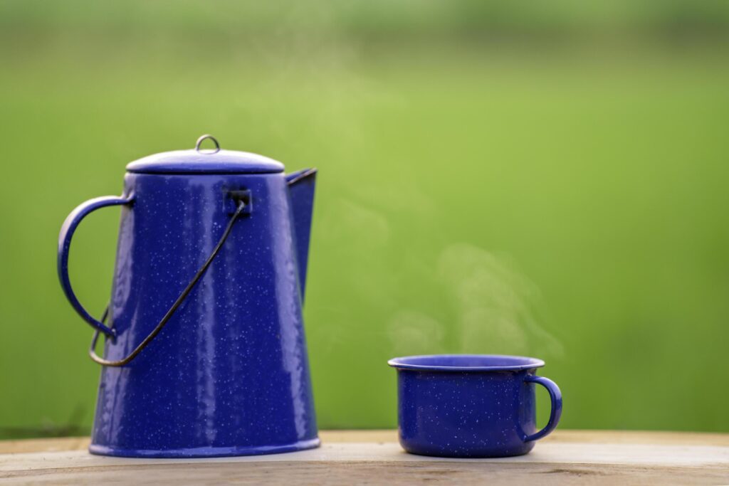 Kettle, blue enamel, and coffee mugs On an old wooden floor, Blurred background of rice fields at sunrise. Stock Free