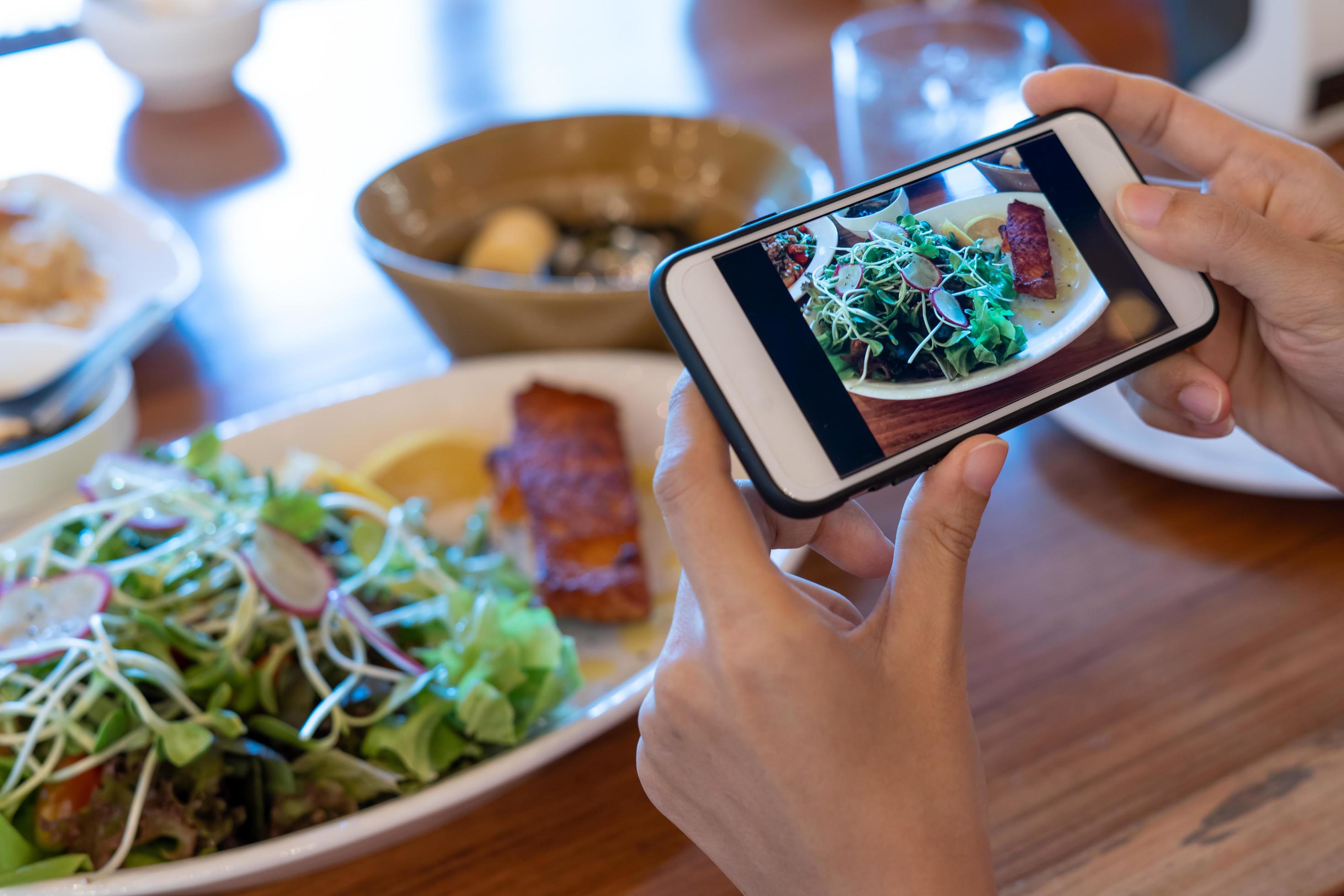 Hand of woman take photo of breakfast with a smartphone on the table. woman is use phone to take pictures of food to review or upload social media. Stock Free