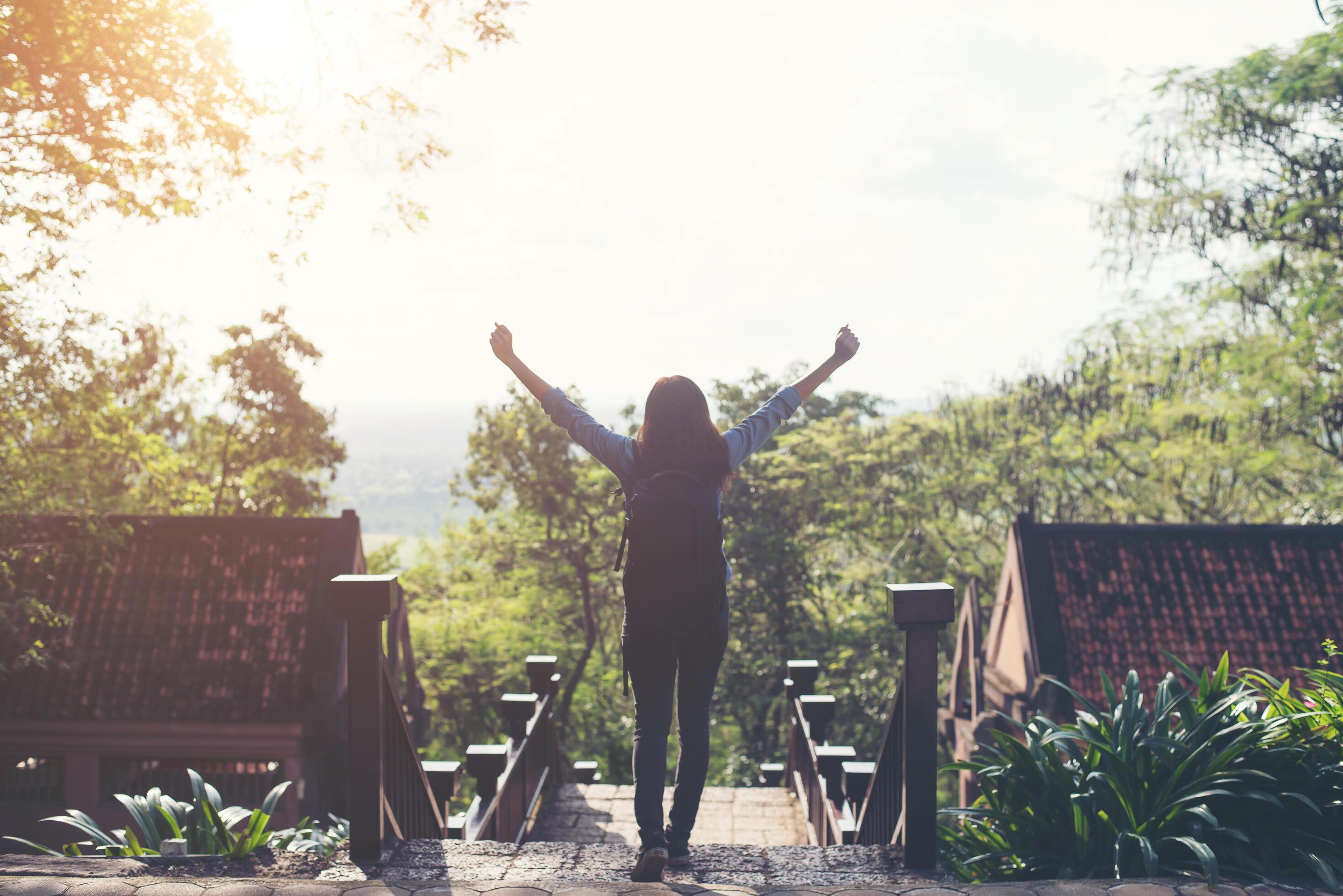 Freedom traveler hipster woman standing with raised arms and enjoying a beautiful nature. Achieved with adventure. Stock Free