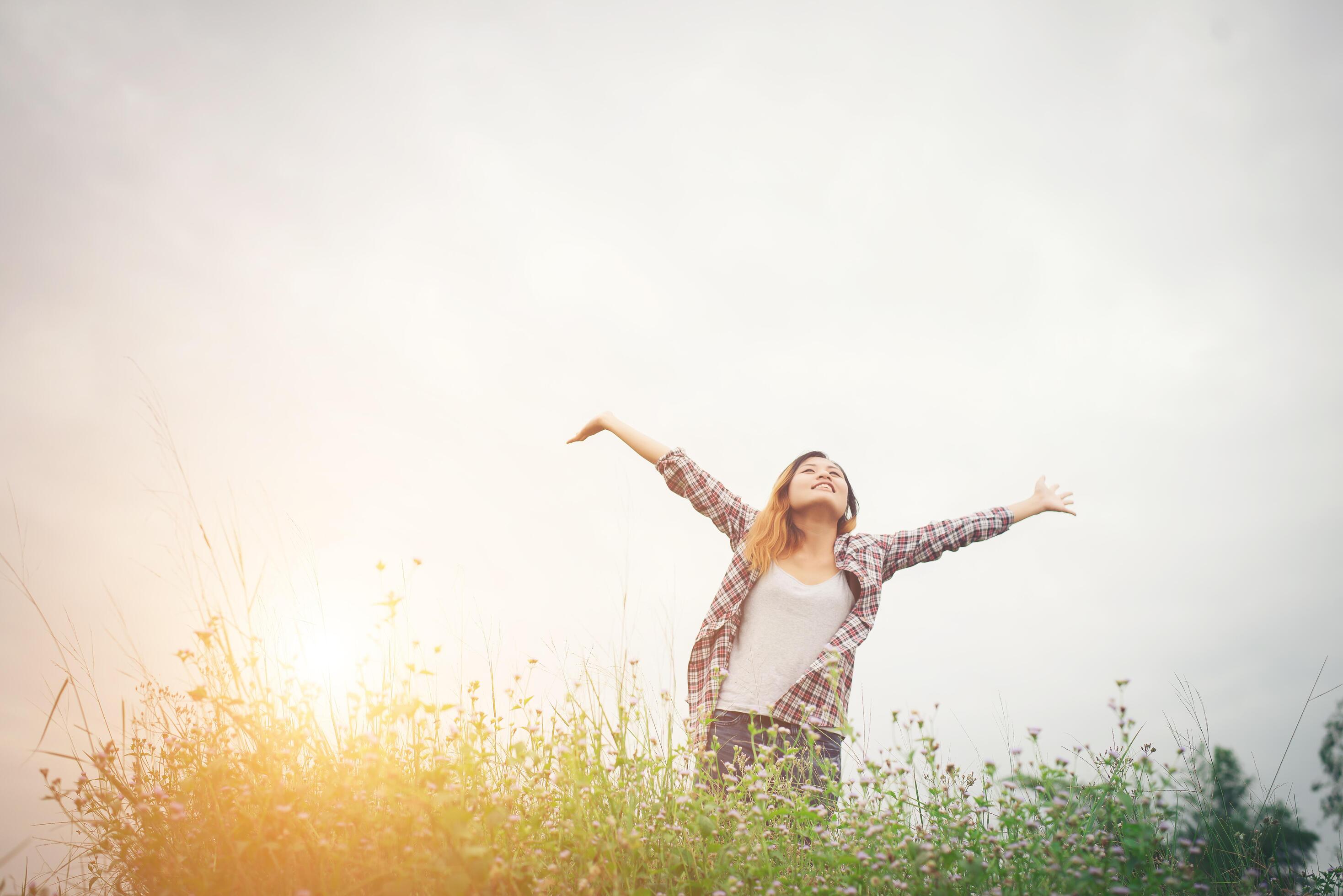 Young beautiful hipster woman in a flower field at sunset. Freedom enjoying with nature. Stock Free