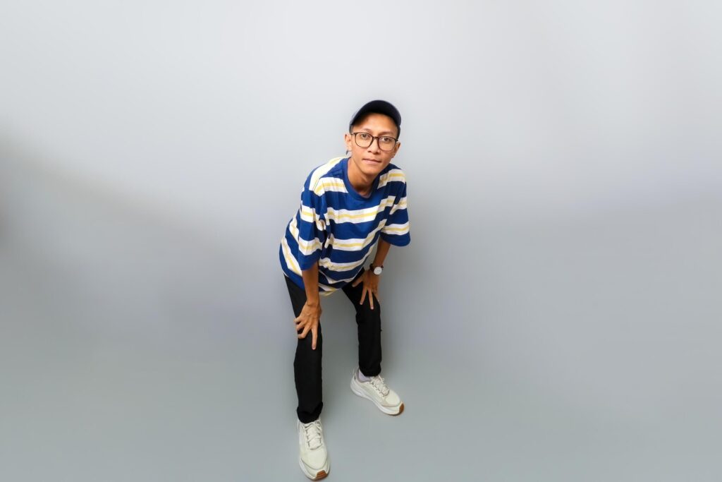 A man in a striped shirt and glasses is standing on a grey background Stock Free