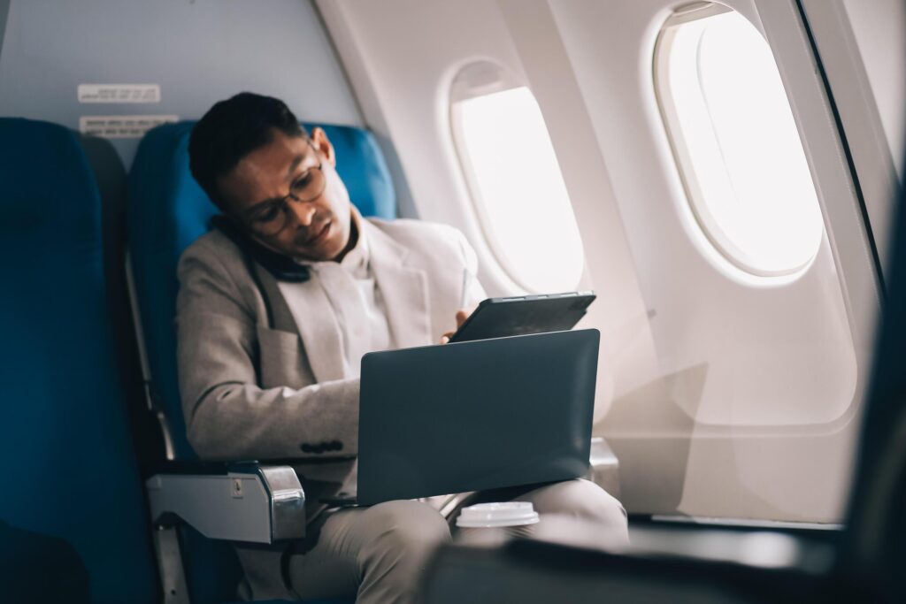 Airplane, travel and portrait of businessman working on laptop computer and smartphone while sitting in airplane. Stock Free