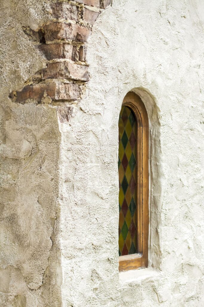 Architectural elements of the wall, windows with colored stained glass. An old wall with cracks. Stock Free