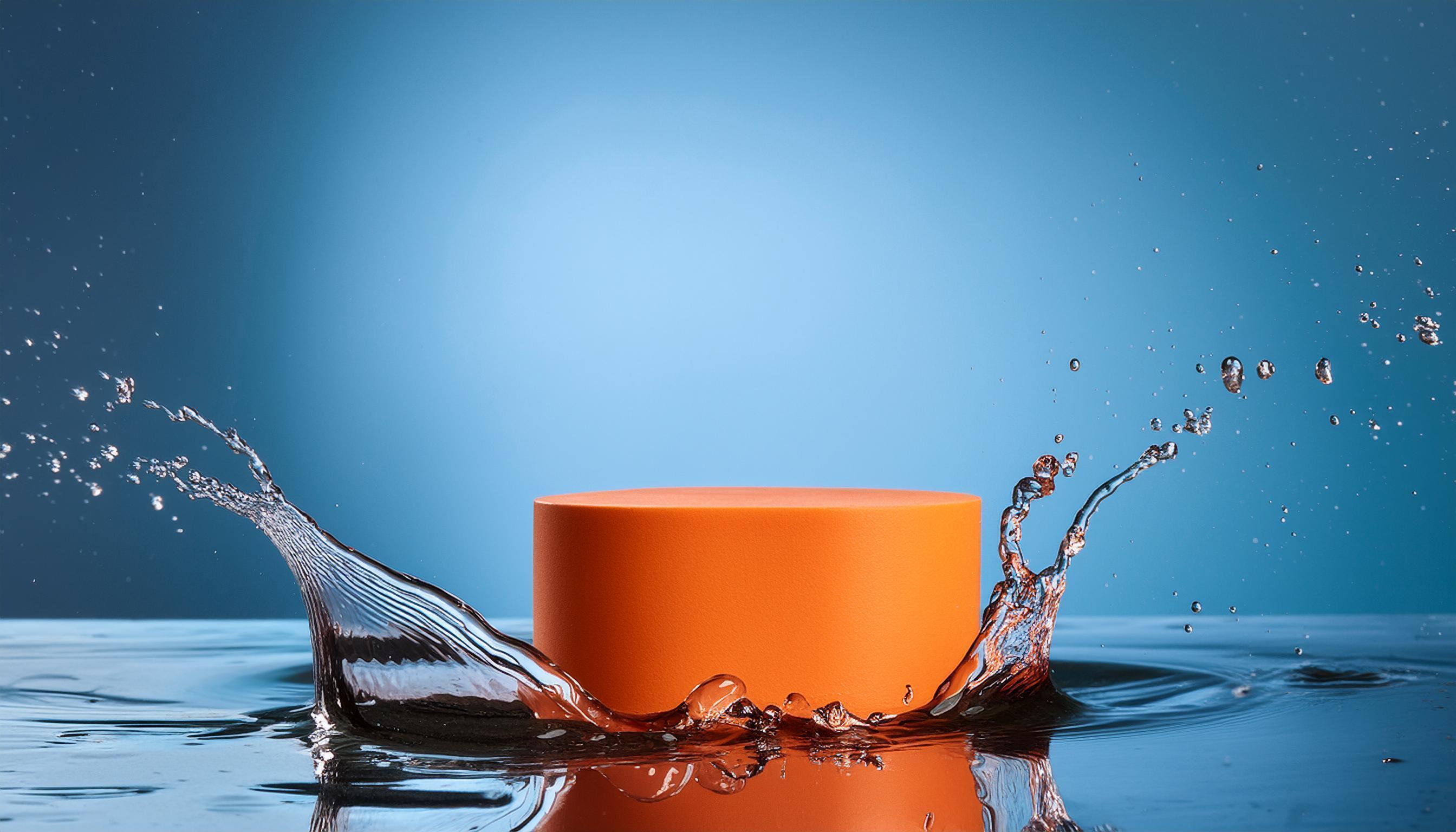 empty orange podium mockup with water splash on a gradient background for product display Stock Free