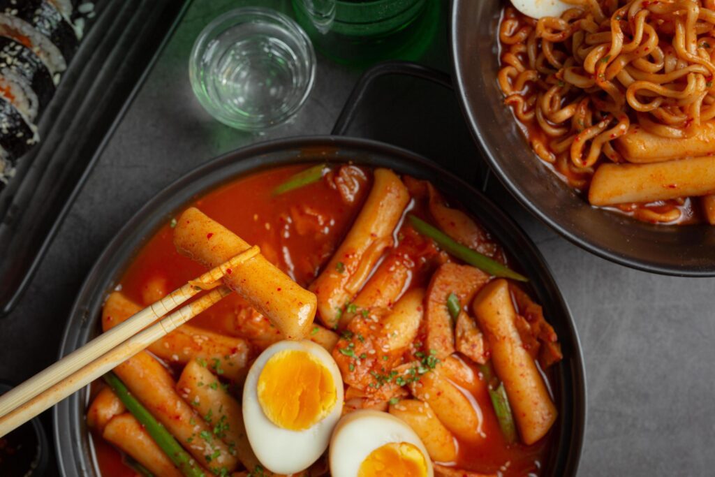 Cheesy Tokbokki korean traditional food on black board background. Lunch dish. Stock Free