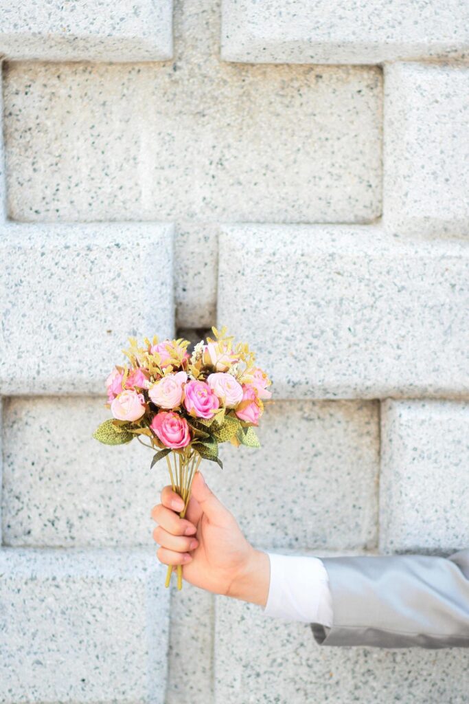 Groom holding a bouquet of pink rose flowers and concrete wall background. Valentine Day for love and celebration Concept. Stock Free