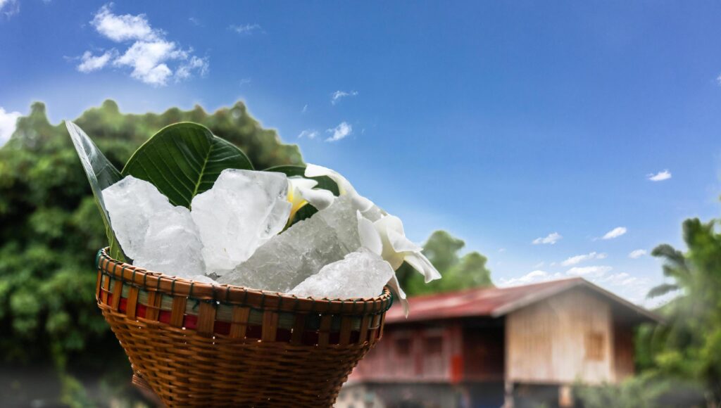 A basket filled with white alum crystals sits on a vibrant green shrub background. Stock Free