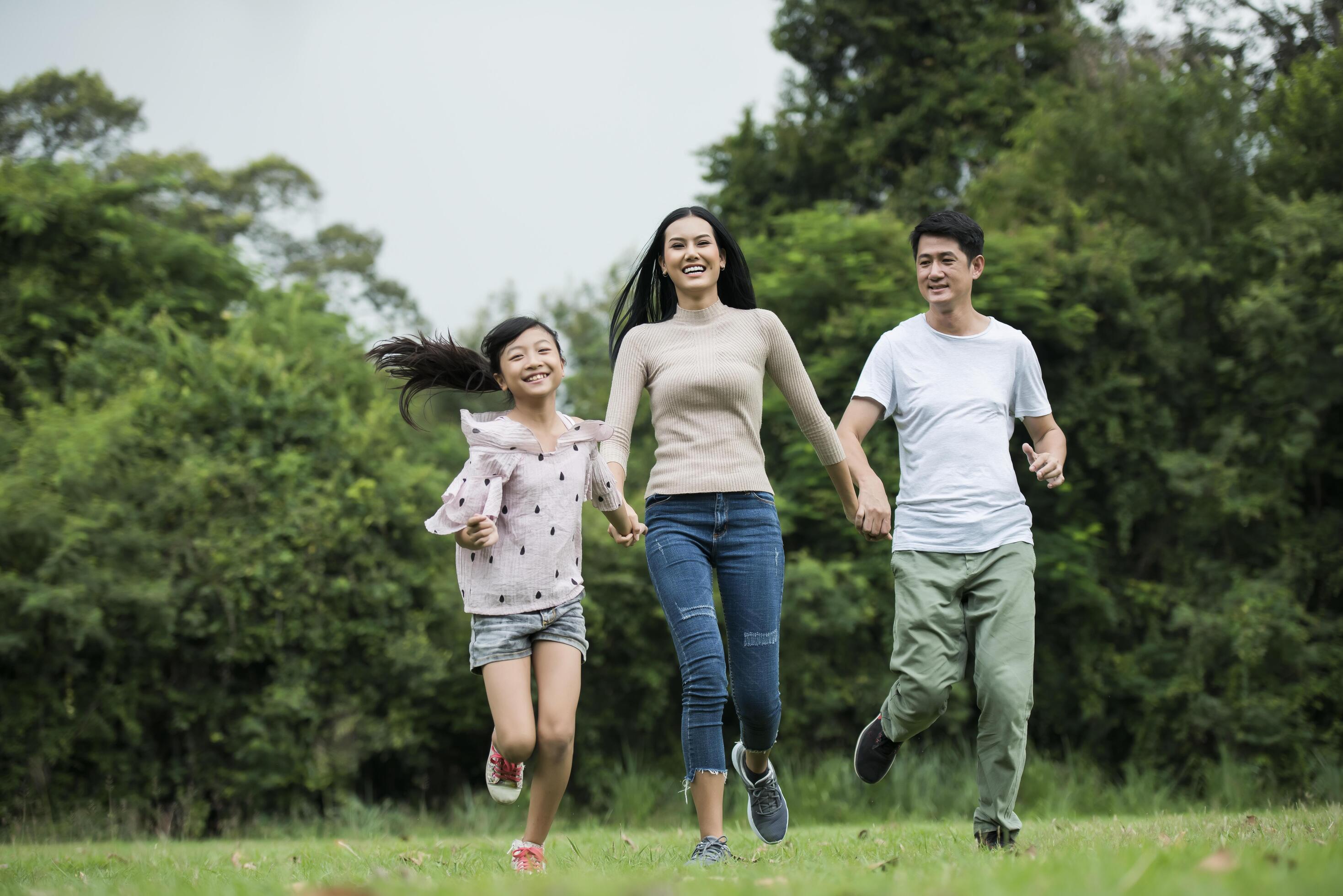 Happy family is having fun Mother, father and daughter are running in park. Stock Free