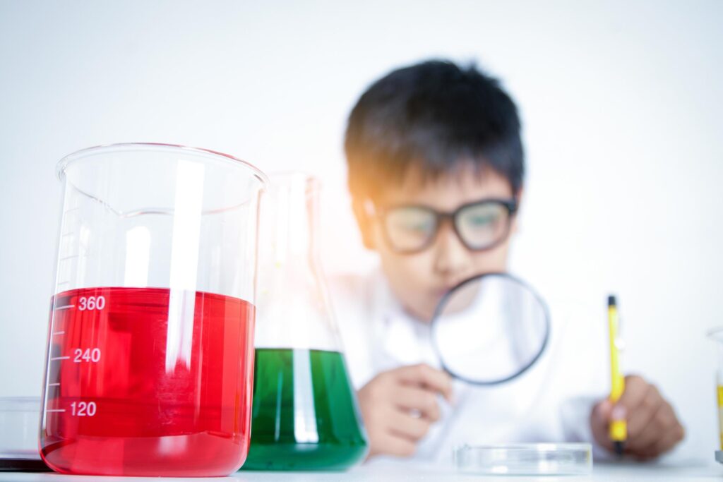 Elementary school boy wearing white dress, doing scientific experiments in the laboratory. Concepts of child education development Stock Free