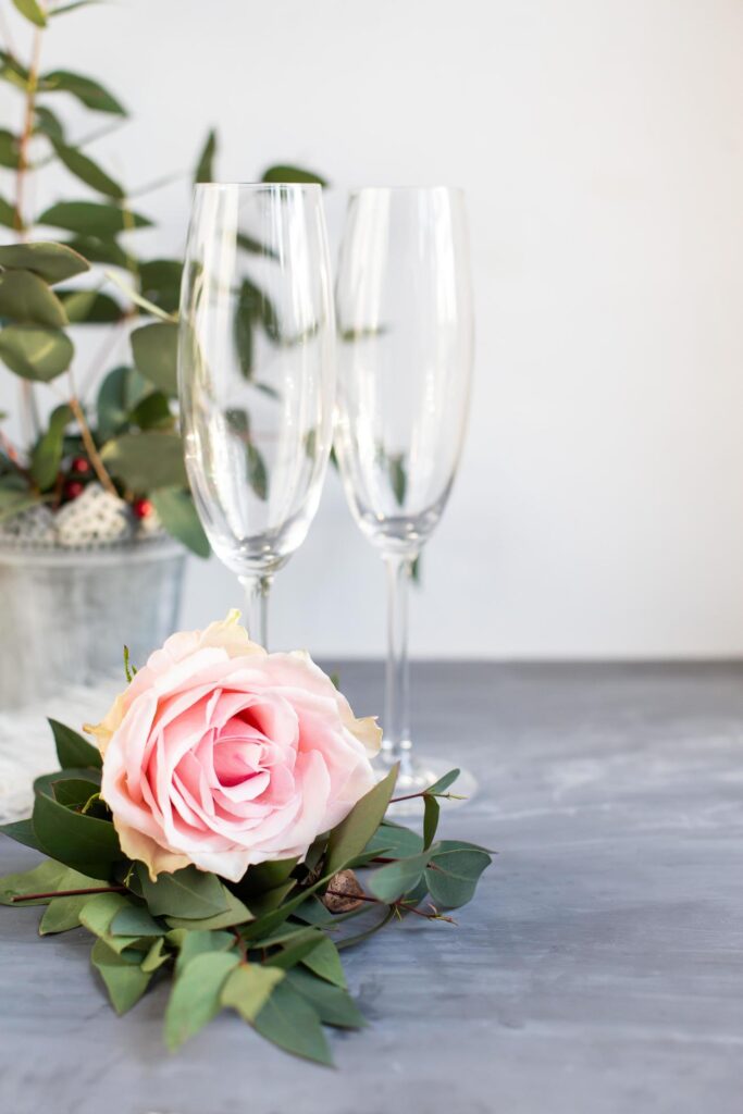 Composition with glass for champagne. Flowers and hearts on grey concrete background. Stock Free