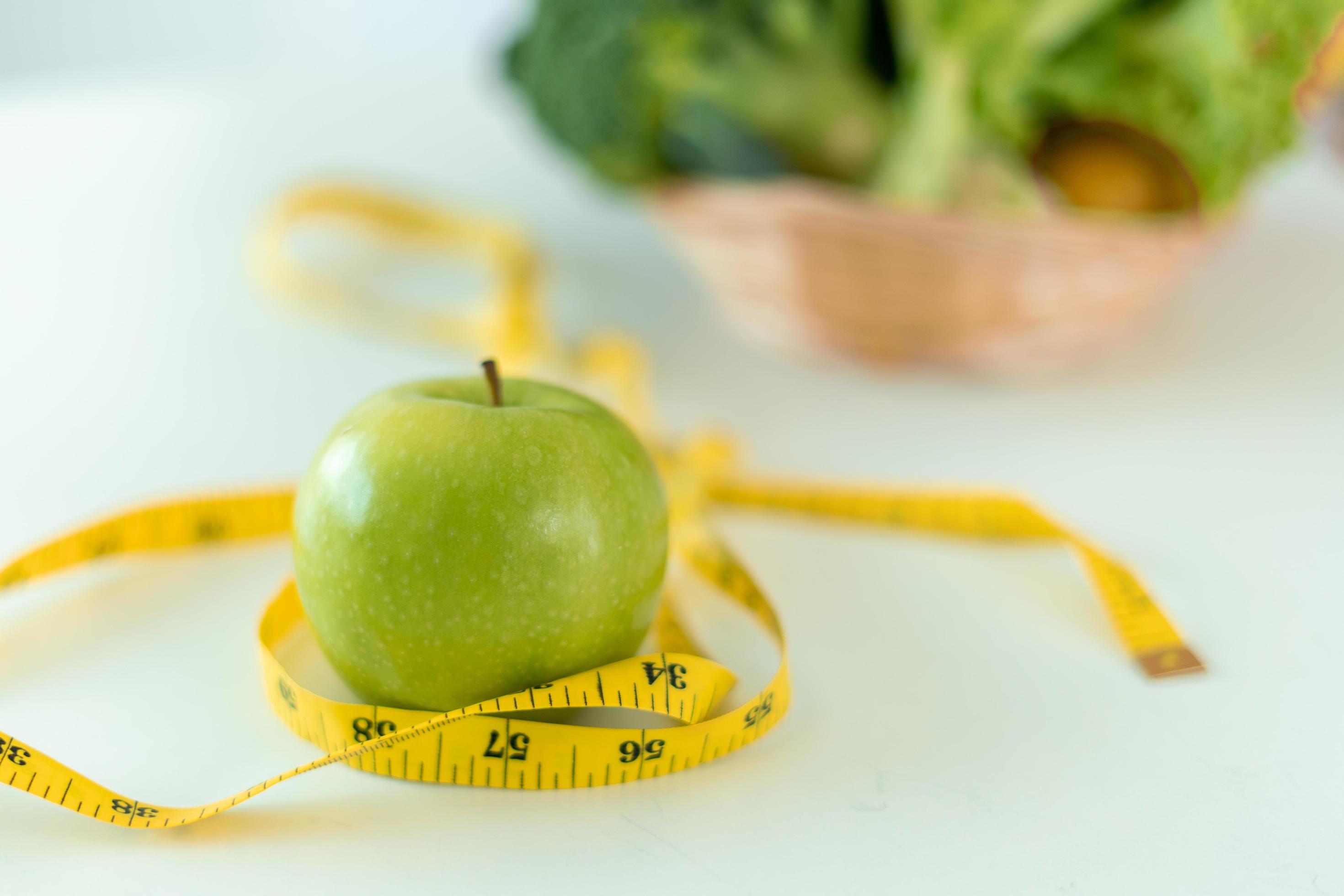 diet concept. Green apples and tape measure with with a gutsy salad on the table. Eating foods with high vitamins for health and weight loss. Stock Free