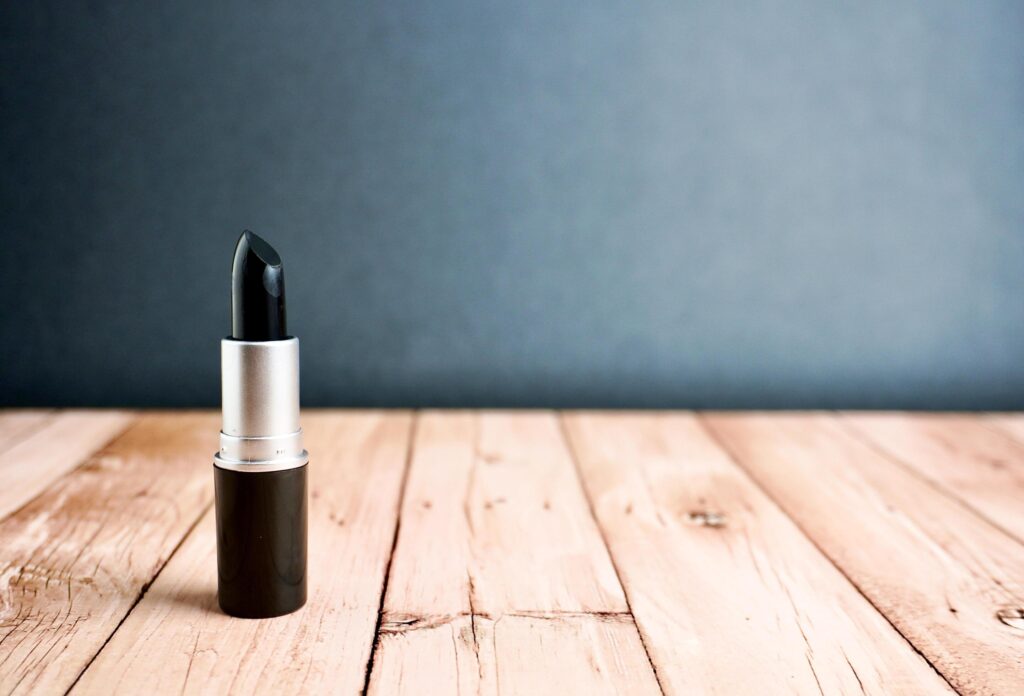 Bold black matte lipstick tube beauty make up products object photography isolated on horizontal ratio wooden surface background. Stock Free