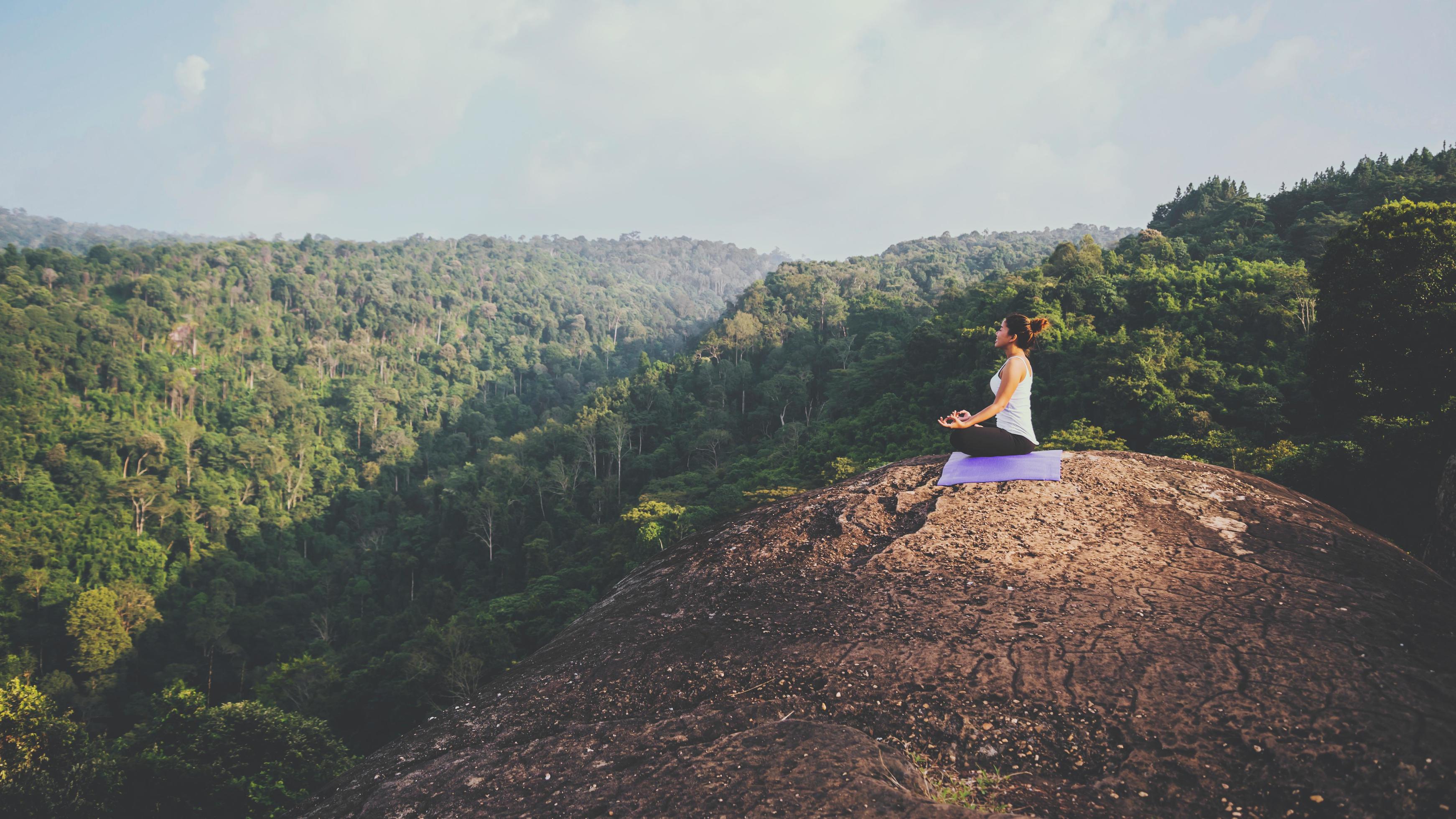 Asian women relax in the holiday. Play if yoga. On the Moutain rock cliff. Nature of mountain forests in Thailand Stock Free