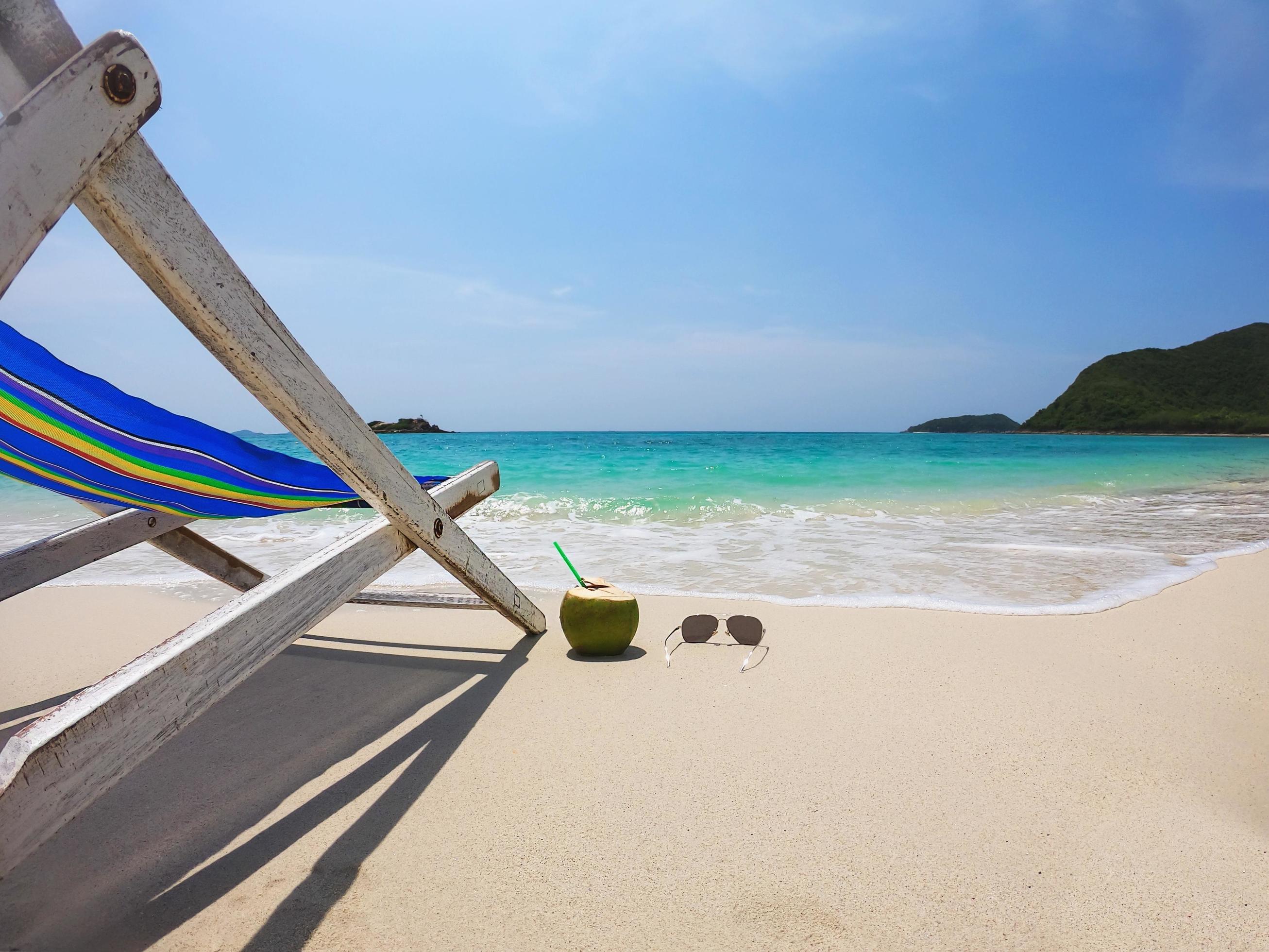 Relax beach chair with fresh coconut on clean sand beach with blue sea and clear sky – sea nature background relax concept Stock Free