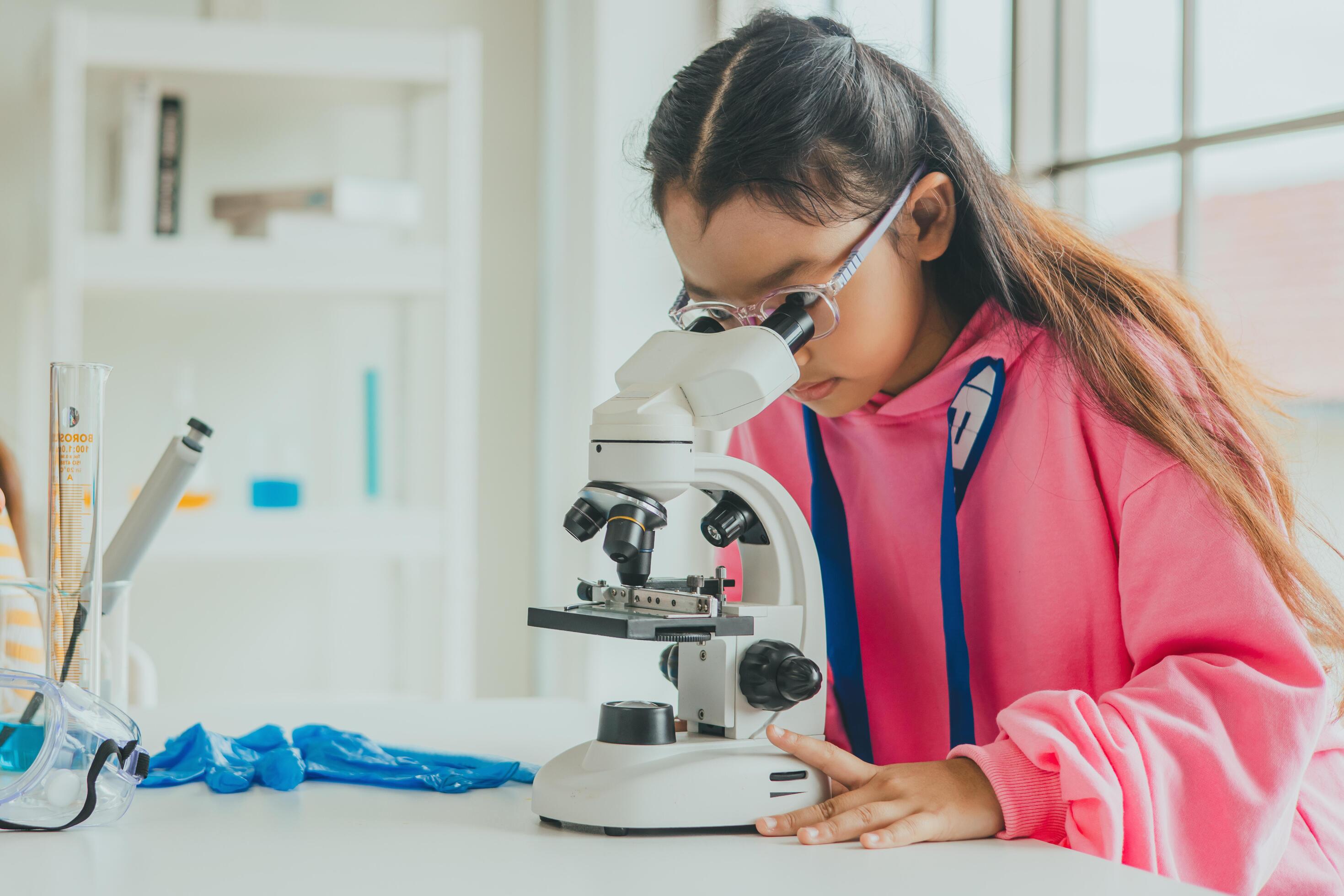 children using microscopes to study science at school Stock Free